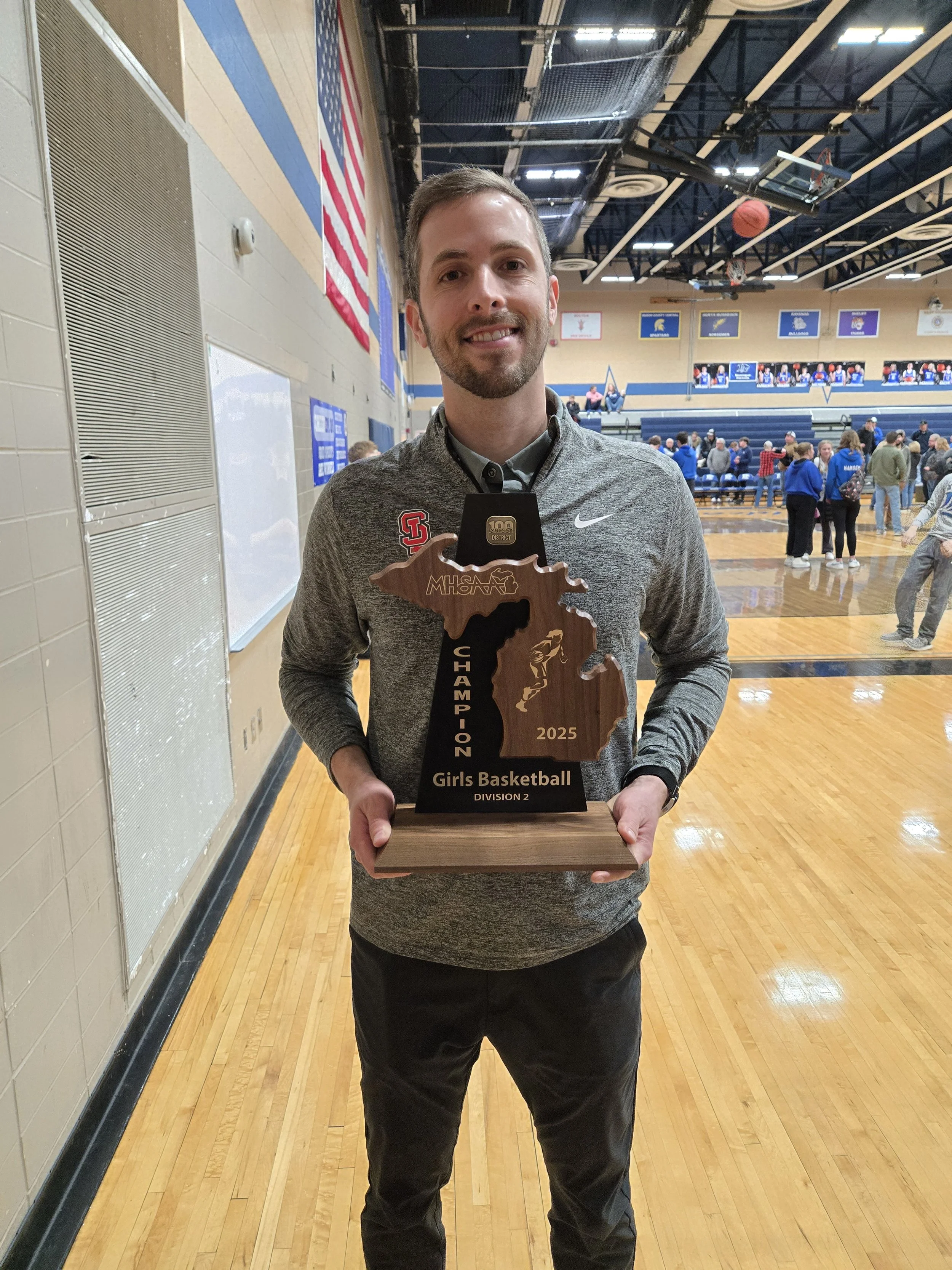 Jacob Uithoven, Grand Haven financial advisor and volunteer youth basketball coach, celebrating a team trophy win.