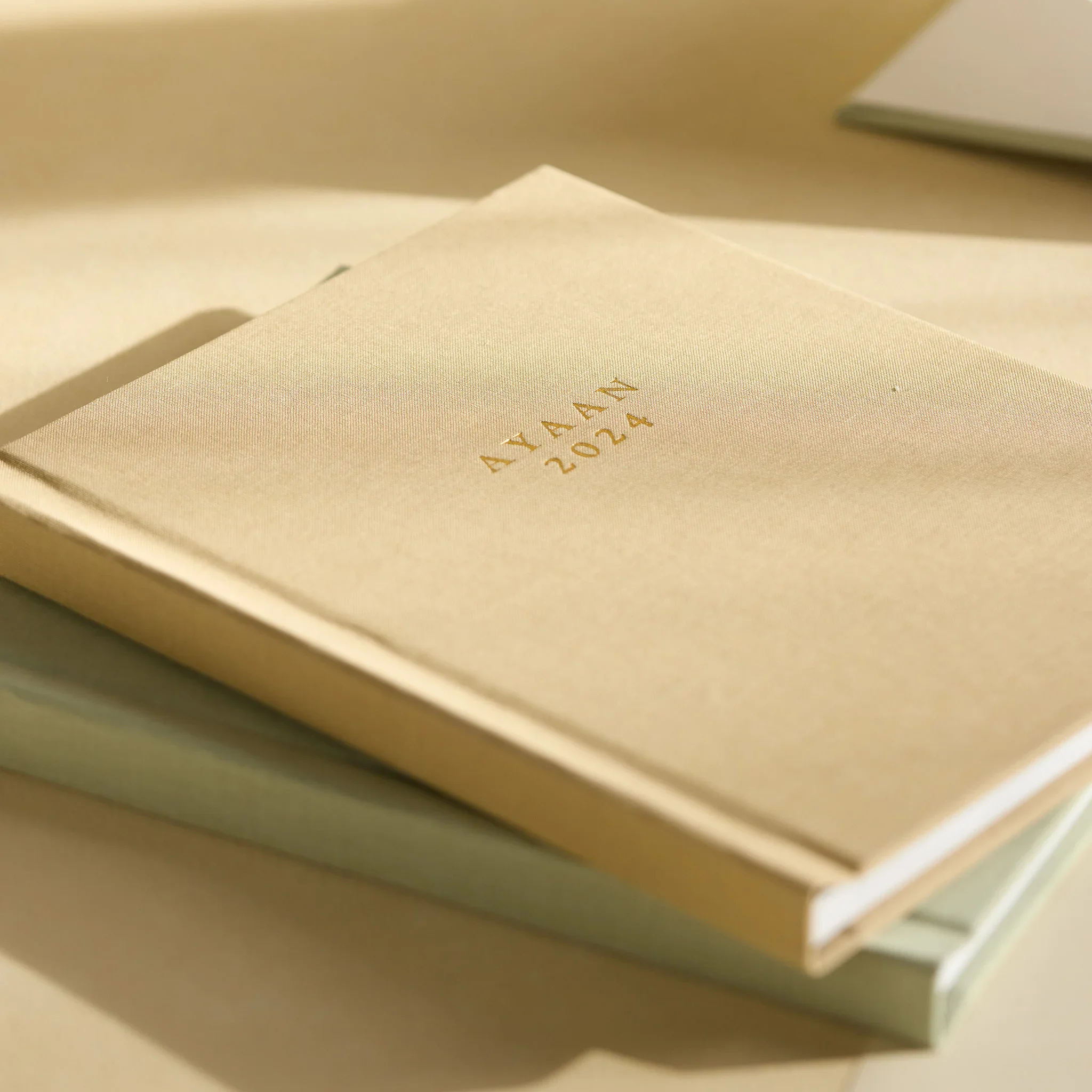 Close-up of a cream-colored textured surface with gold lettering, possibly a book cover or packaging.