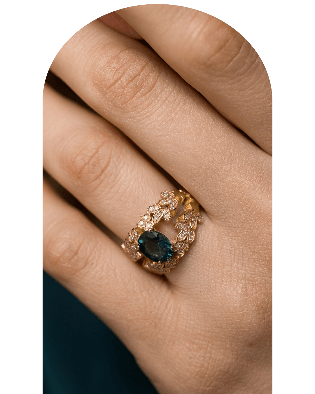 Bague en or avec une pierre précieuse noire et de petits diamants autour, portée sur un doigt.