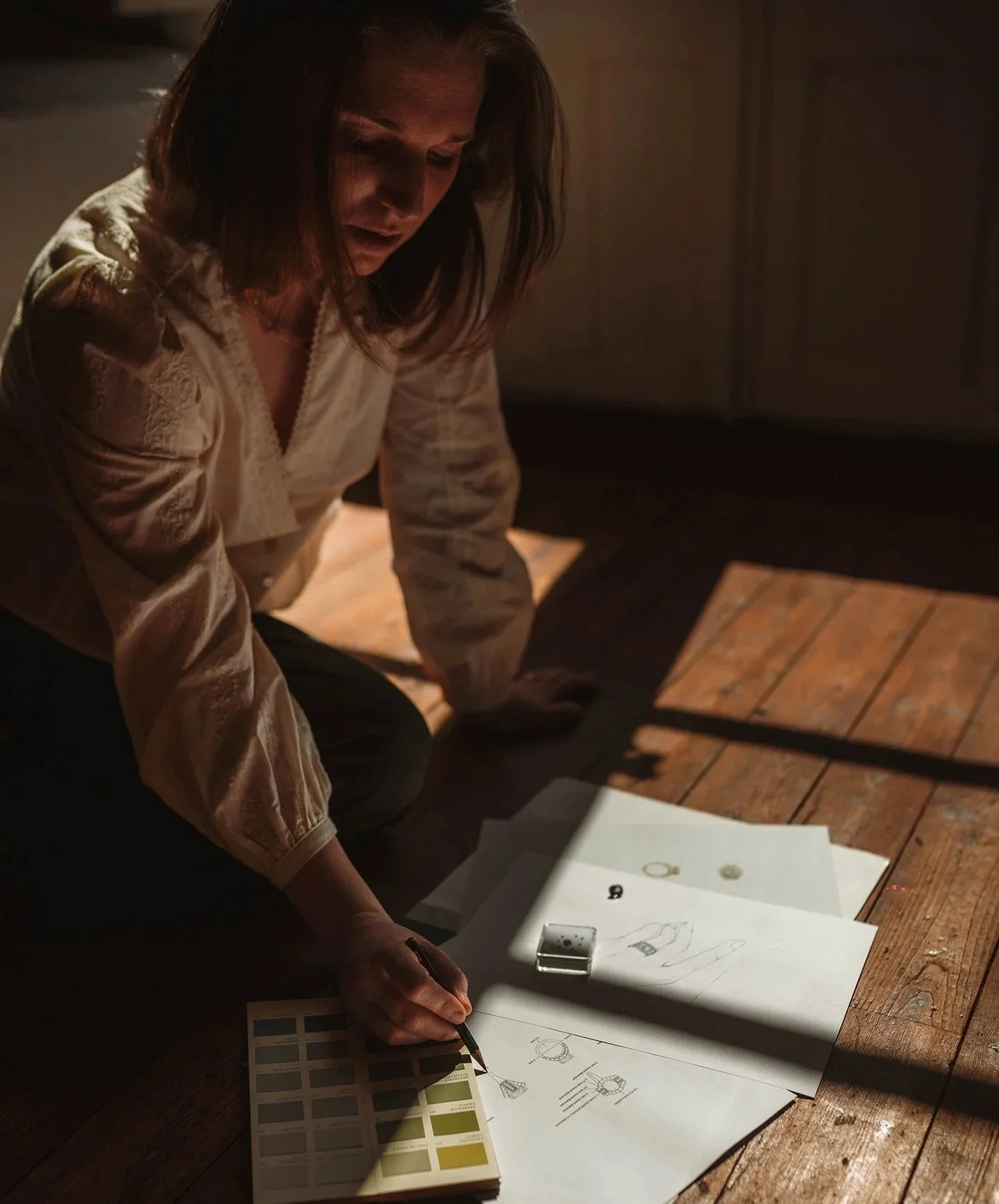 Photo de la créatrice Ombeline Mar!ès dessinant avec autours d'elle des gemmes