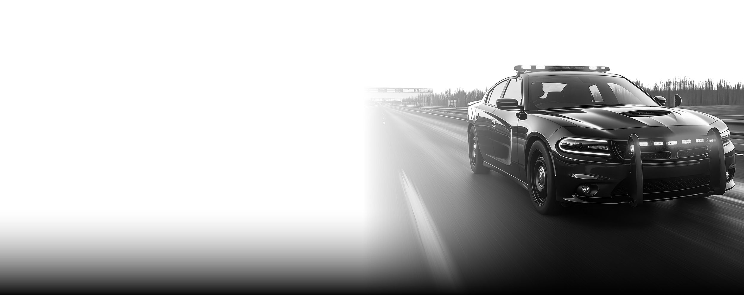 A black police car driving on a highway in a black and white photo.
