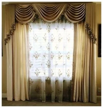 Decorative window with layered curtains, including sheer white fabric with floral embroidery and heavier gold drapes with valances.