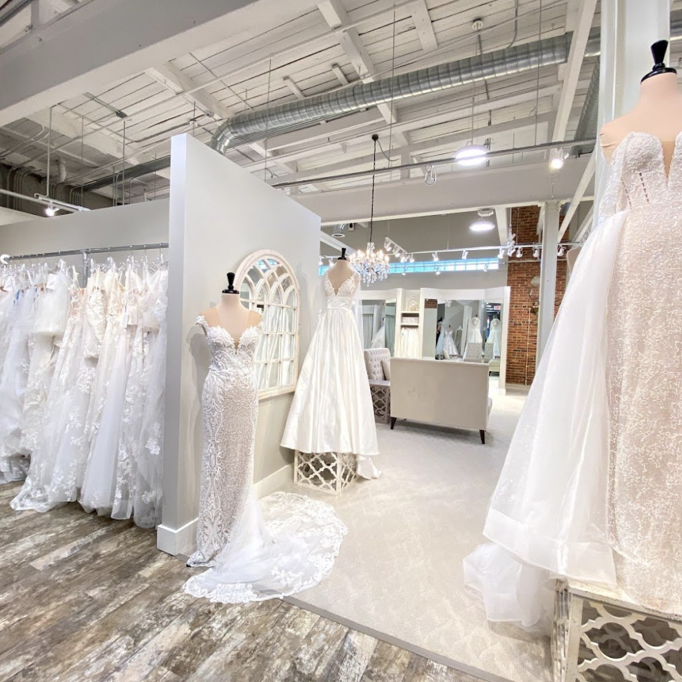 Wedding dresses displayed on mannequins and racks inside a bridal boutique with modern industrial decor.