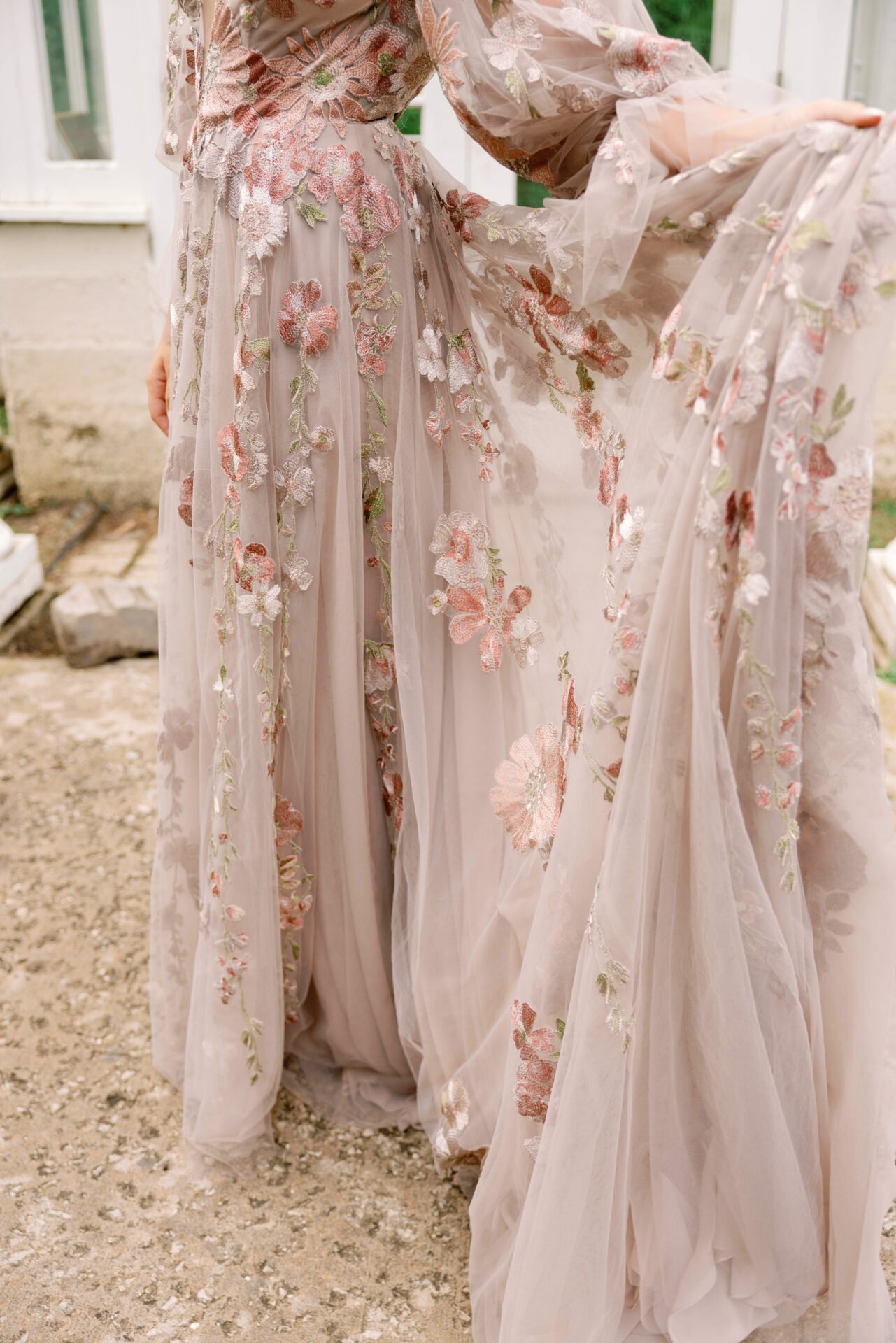 Close-up of a light pink, floral embroidered dress with sheer fabric and puffed sleeves, draped outdoors.