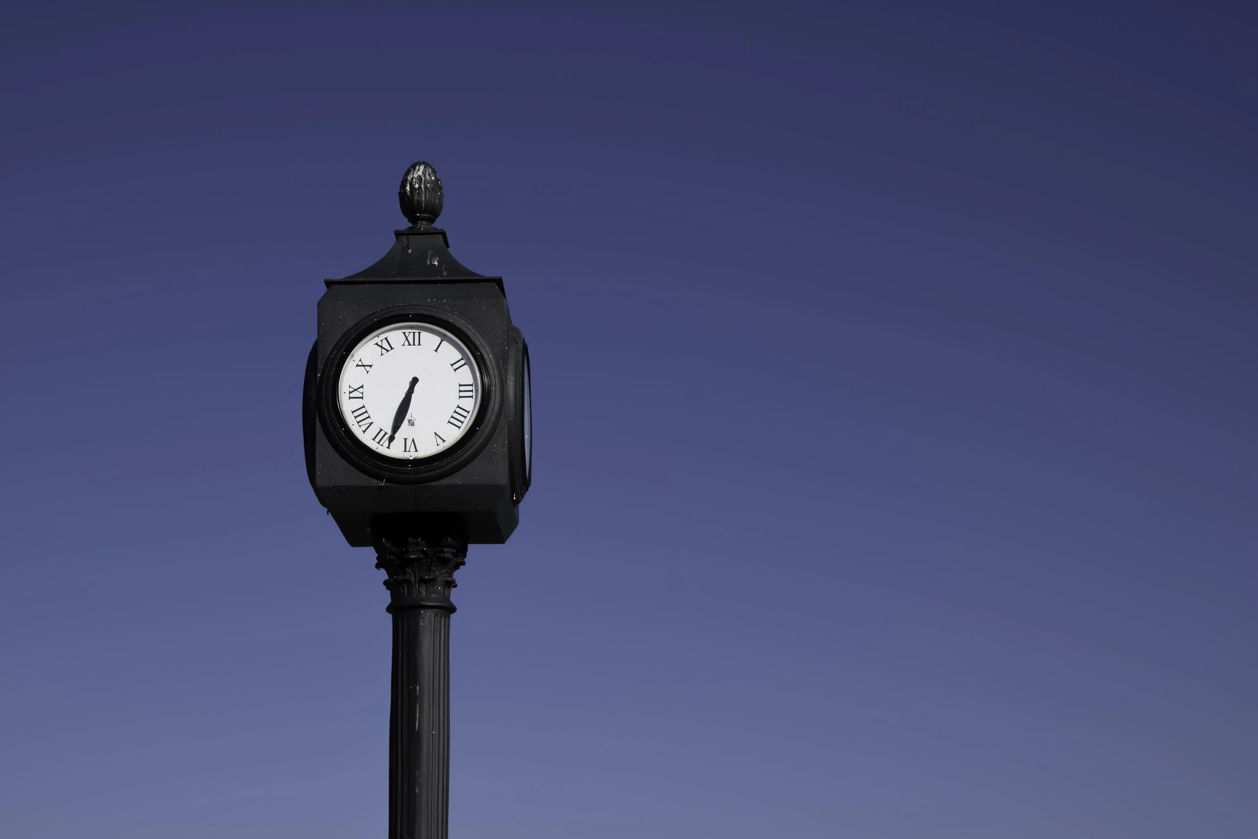 Black clock in front of a blue sky