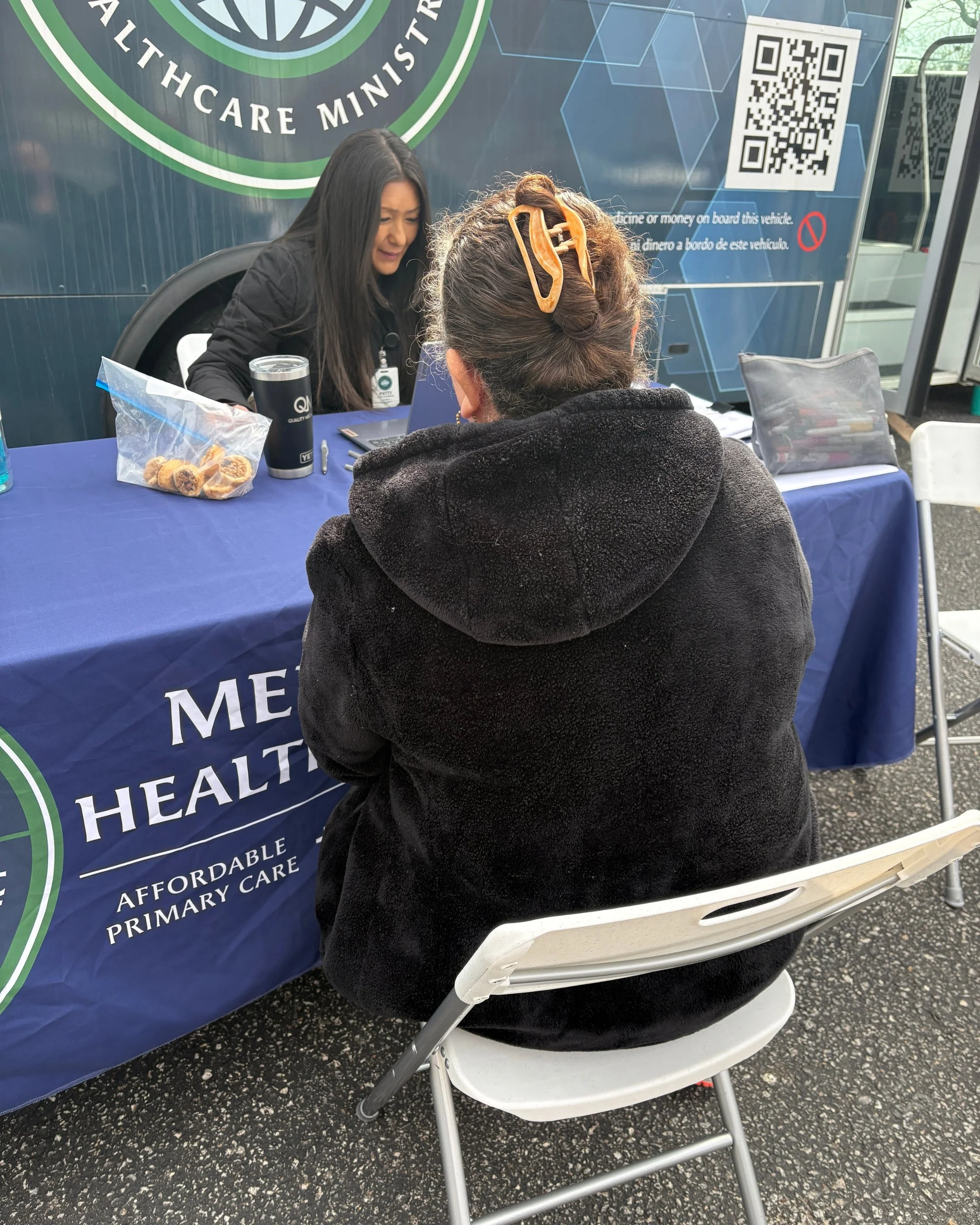 A Mercy & Truth Community Health Worker talks with a neighbor outside the Mobile Health Clinic at May's F.I.R.S.T. Tuesday women's health event.