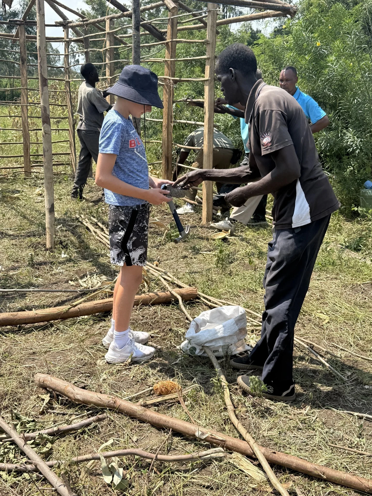 A young boy and an adult work together in Kenya with the Mercy & Truth Medical Missions team, building homes for families in need. This hands-on outreach, part of the Mercy & Truth Healthcare Ministry, provides Life-Changing Care.