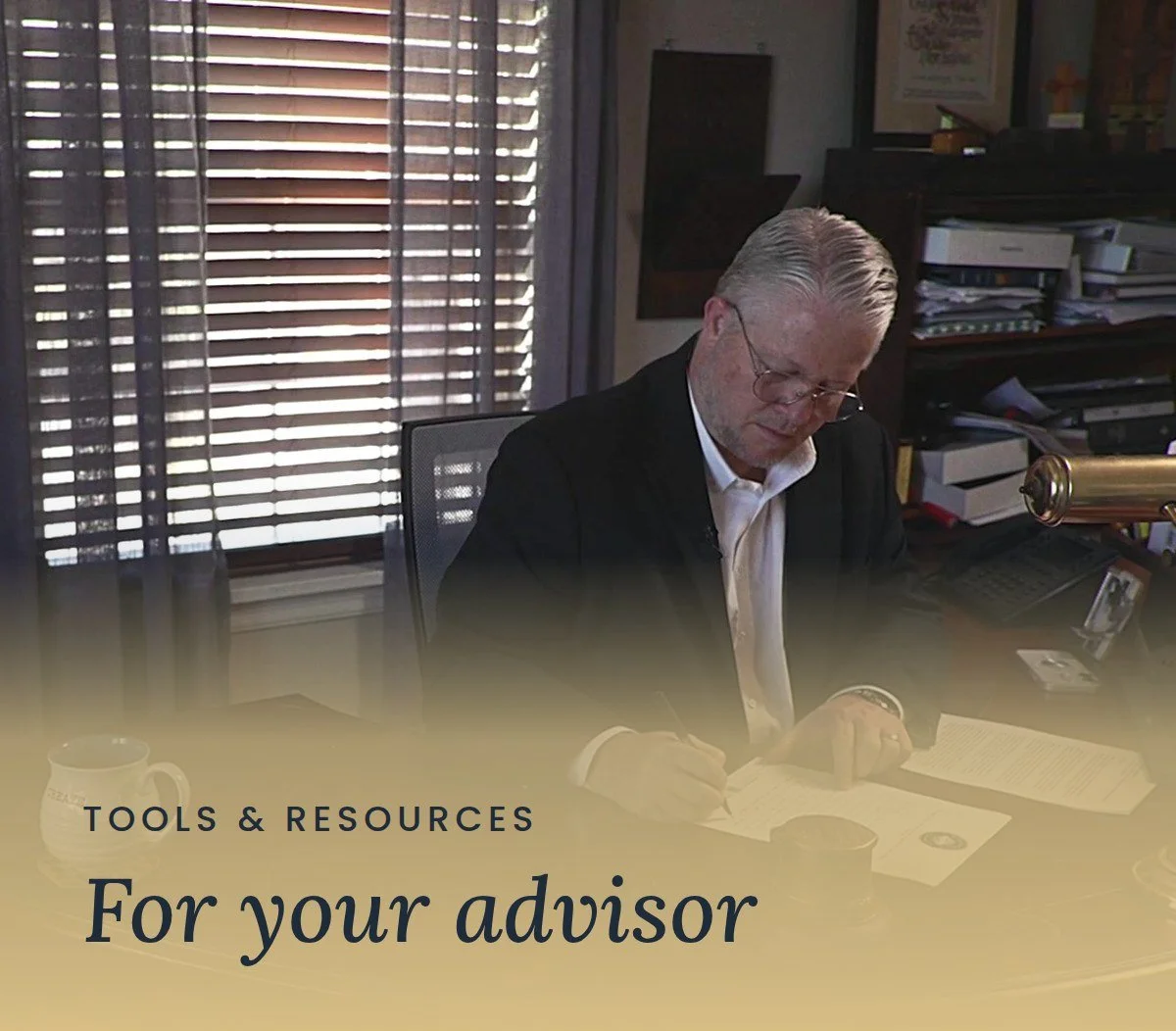 Mercy & Truth CEO Brent Morris reviews and signs paperwork at his office desk. Text reads "Tools & Resources: For your advisor."