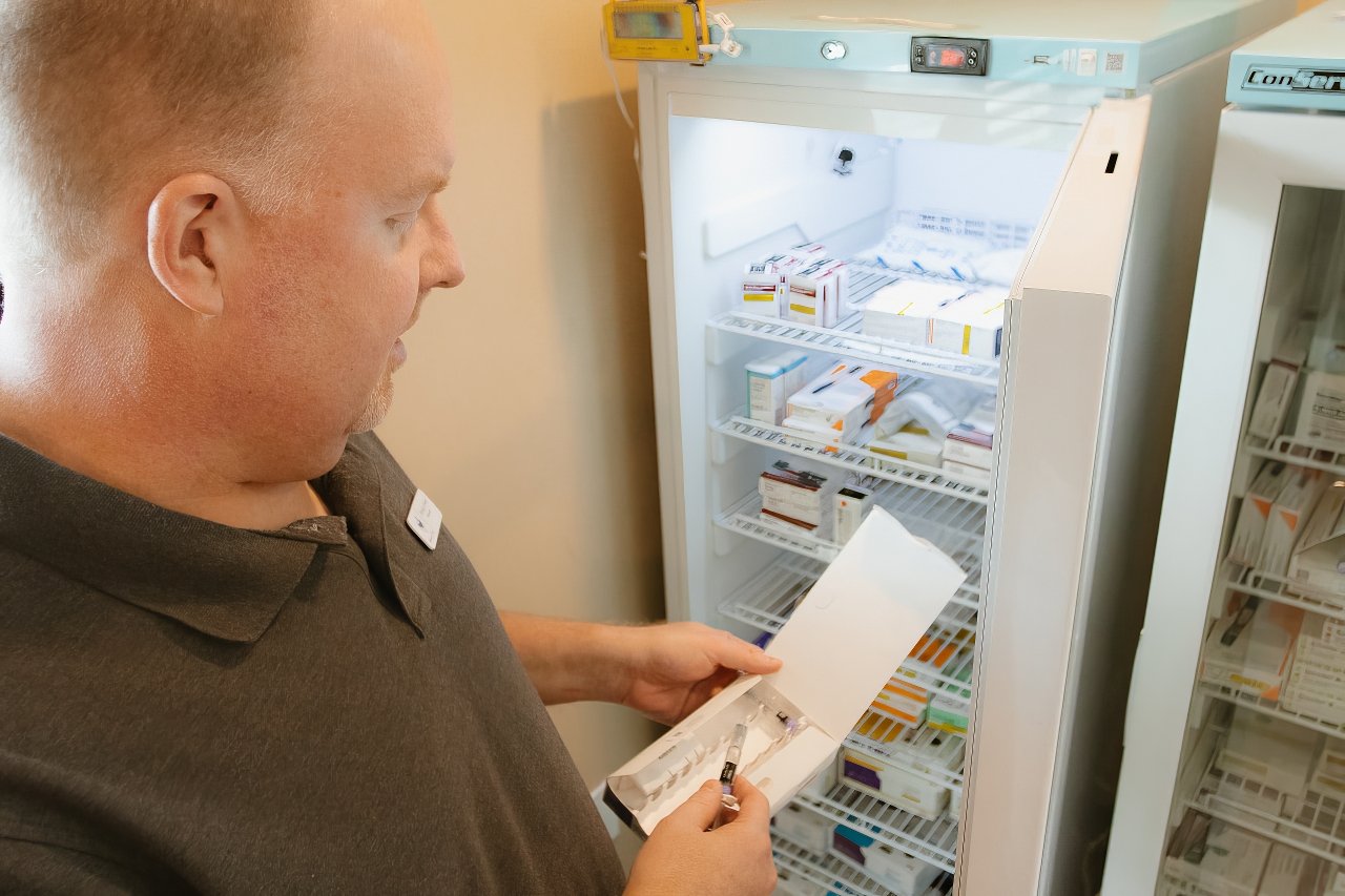 Mercy & Truth pharmacist checking refrigeration units to maintain proper medication storage standards.