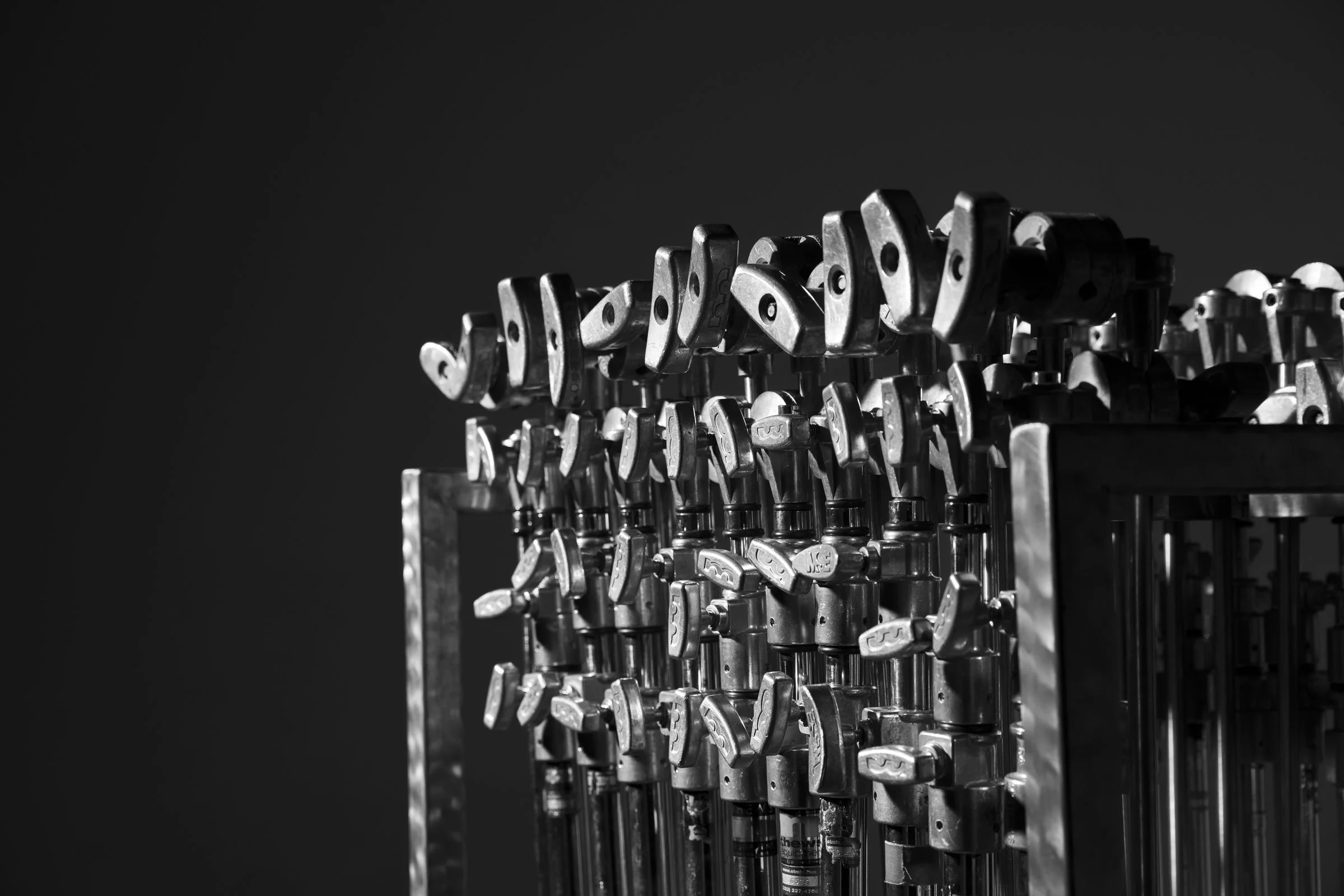 Black and white photo of a metal display rack filled with various metal keys or key-like objects arranged in rows.