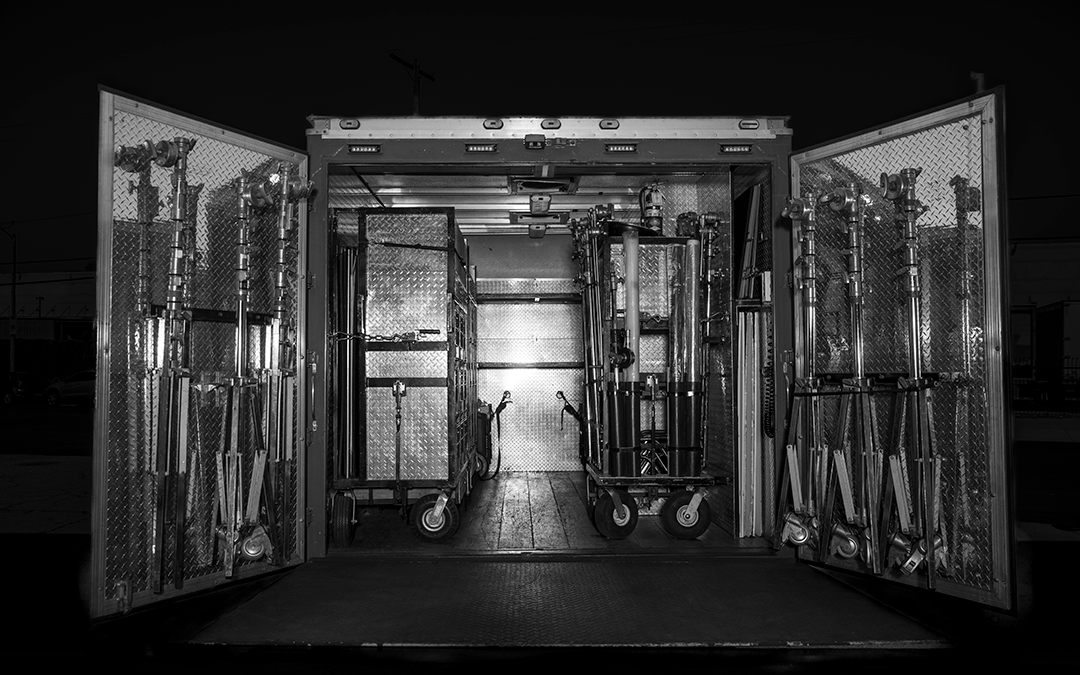Interior of a fire truck with equipment and ladders stored inside, open doors revealing tools and supplies.