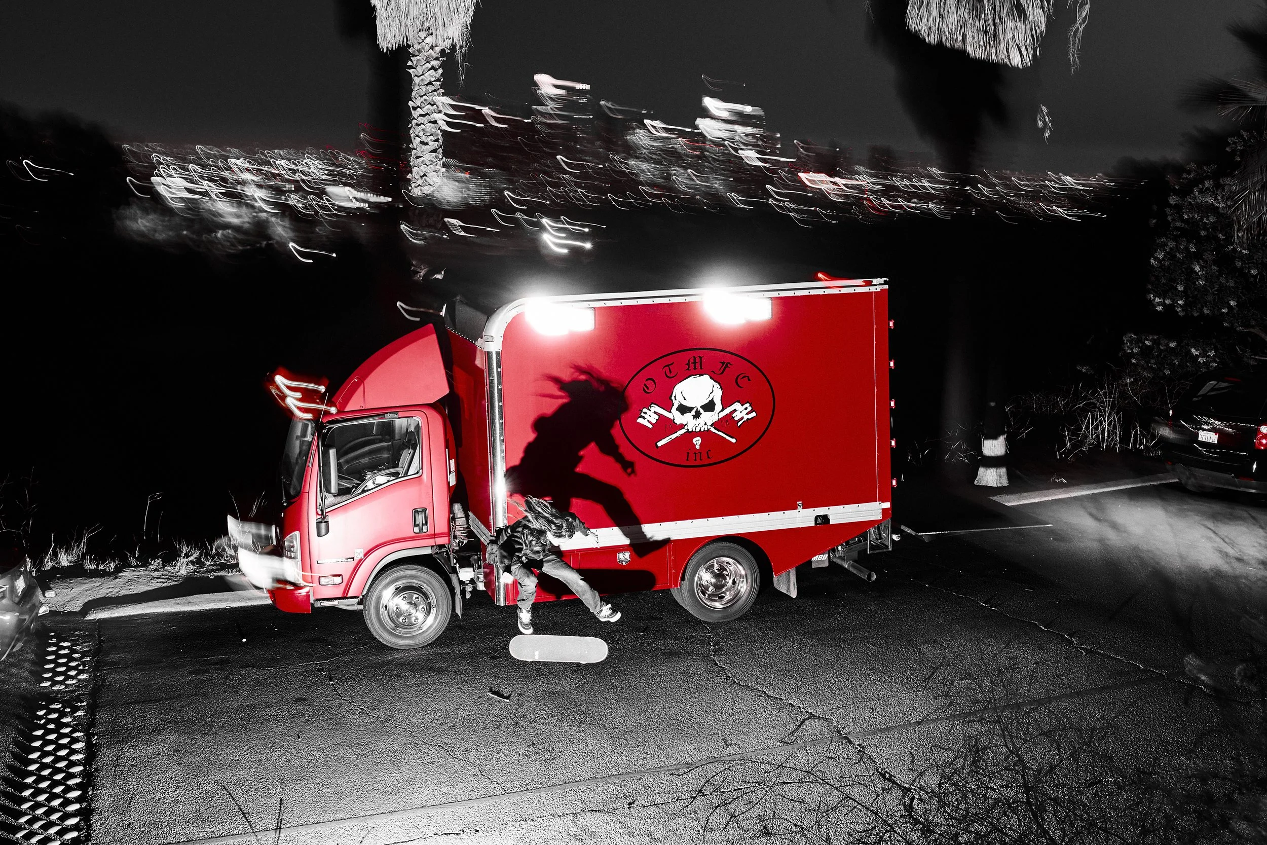 Night scene featuring a red delivery truck with a skull logo, a person entering the truck, and blurred city lights in the background.