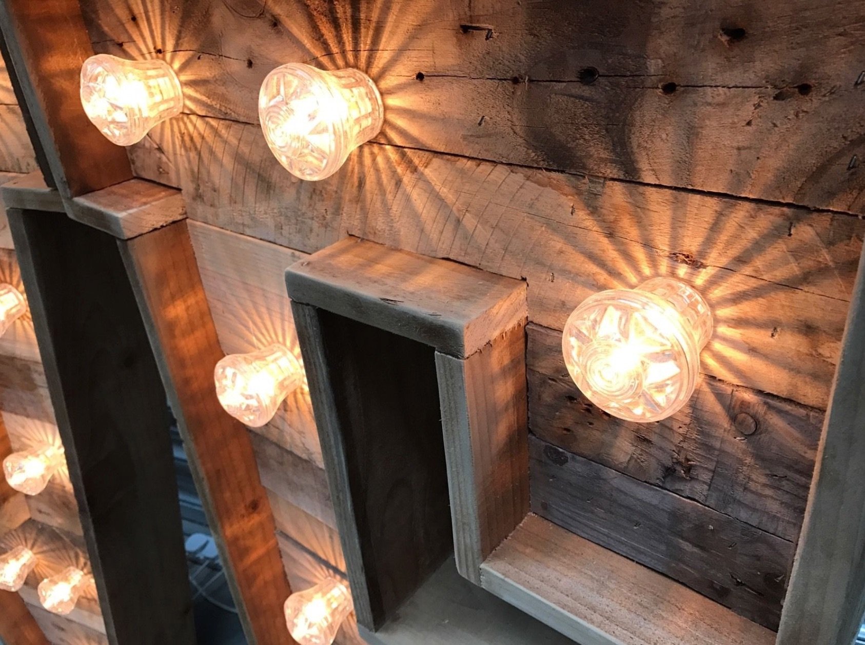 Close-up of a rustic wooden wall with glass light fixtures emitting warm light.