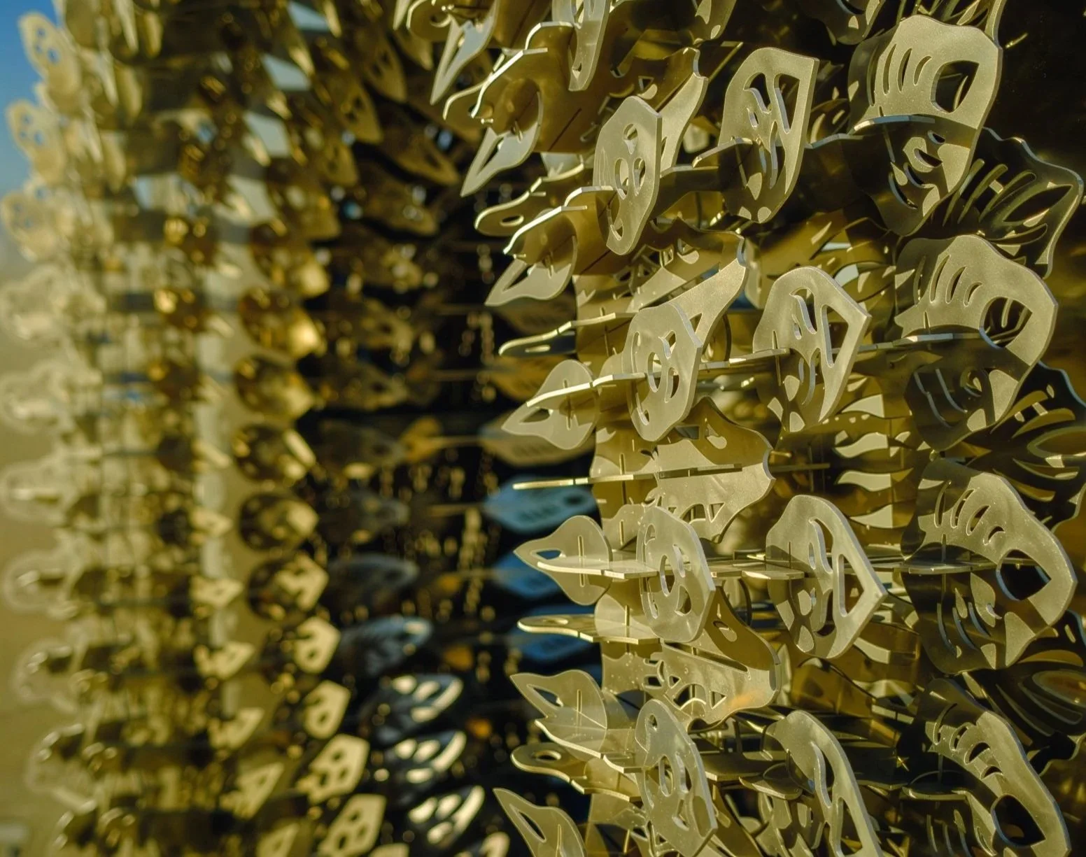 Close view along the edge of the Burning Man ring sculpture, rows of laser-cut petals catching low golden sunlight against blue sky.