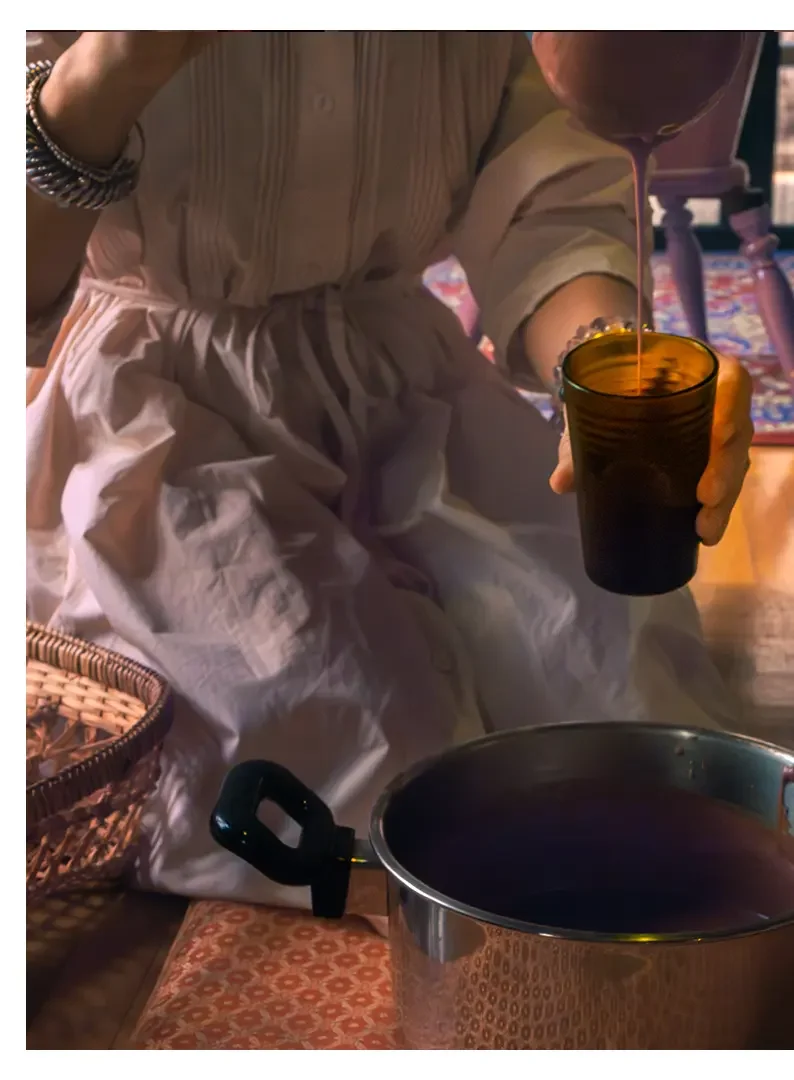 Person pouring cacao into a glass from a pot.