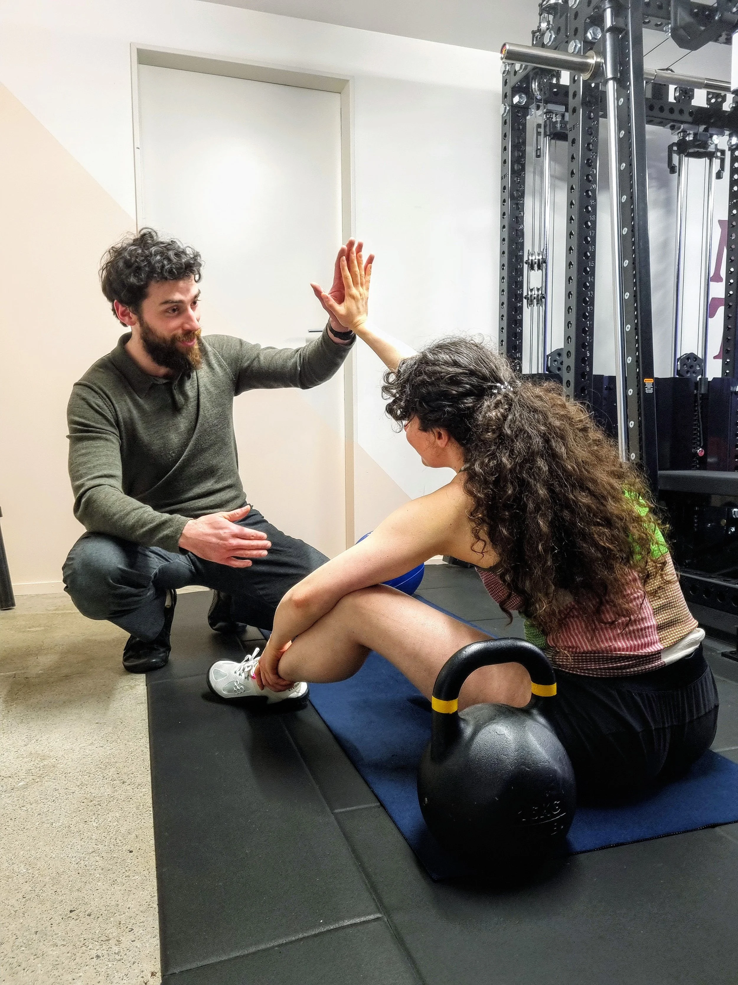 A local Karori woman with curly hair high fives personal trainer Julian Etchegoin, founder and personal trainer at Craft Fitness Studio.