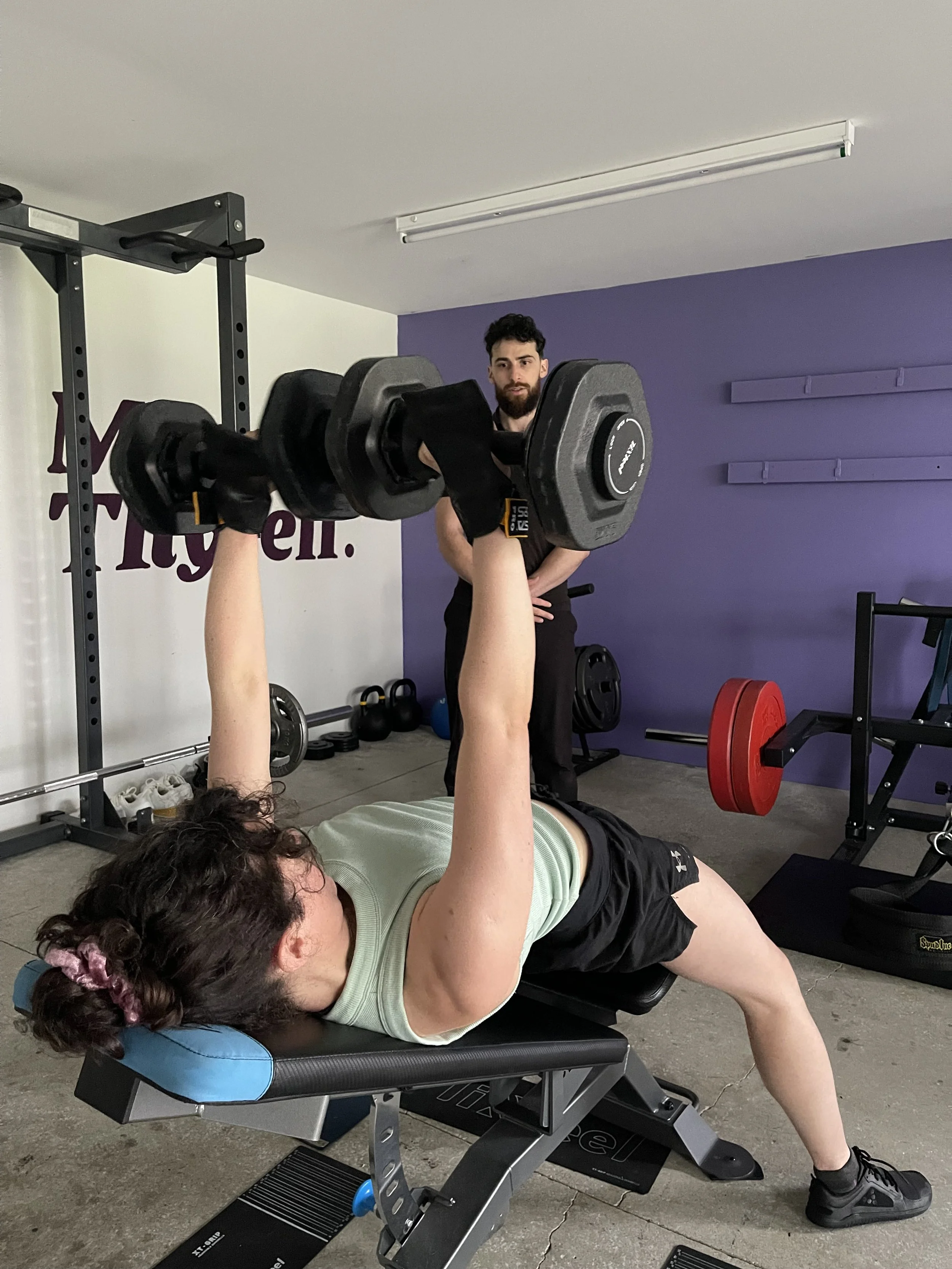 Personal trainer in Karori instructing female client on weight lifting with dumbells