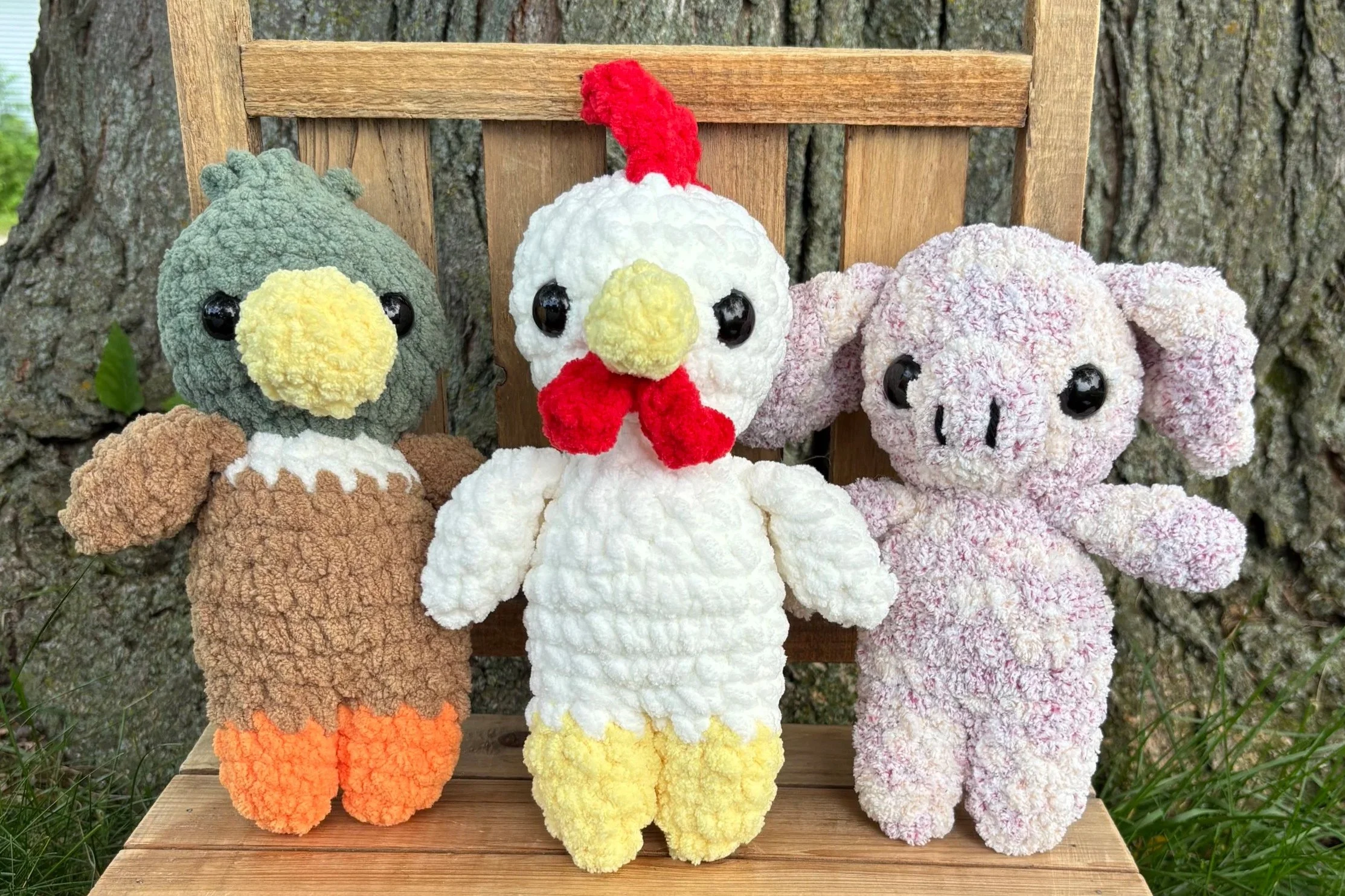 Crochet farm animal plushie bundle sitting on wooden bench outdoors