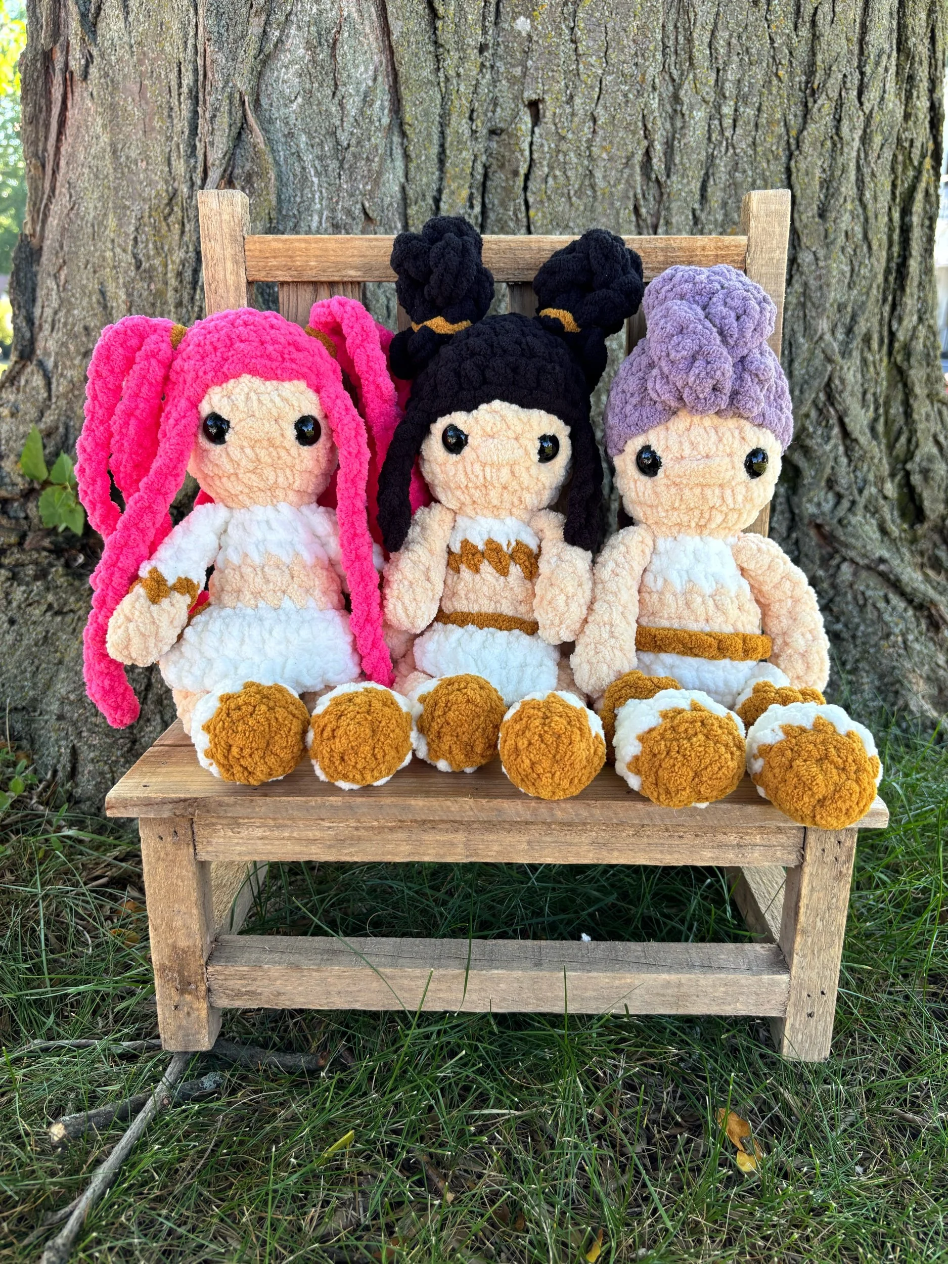 Three handmade crochet  K-pop dolls, Mira, Zoey, and Rumi, on wooden bench