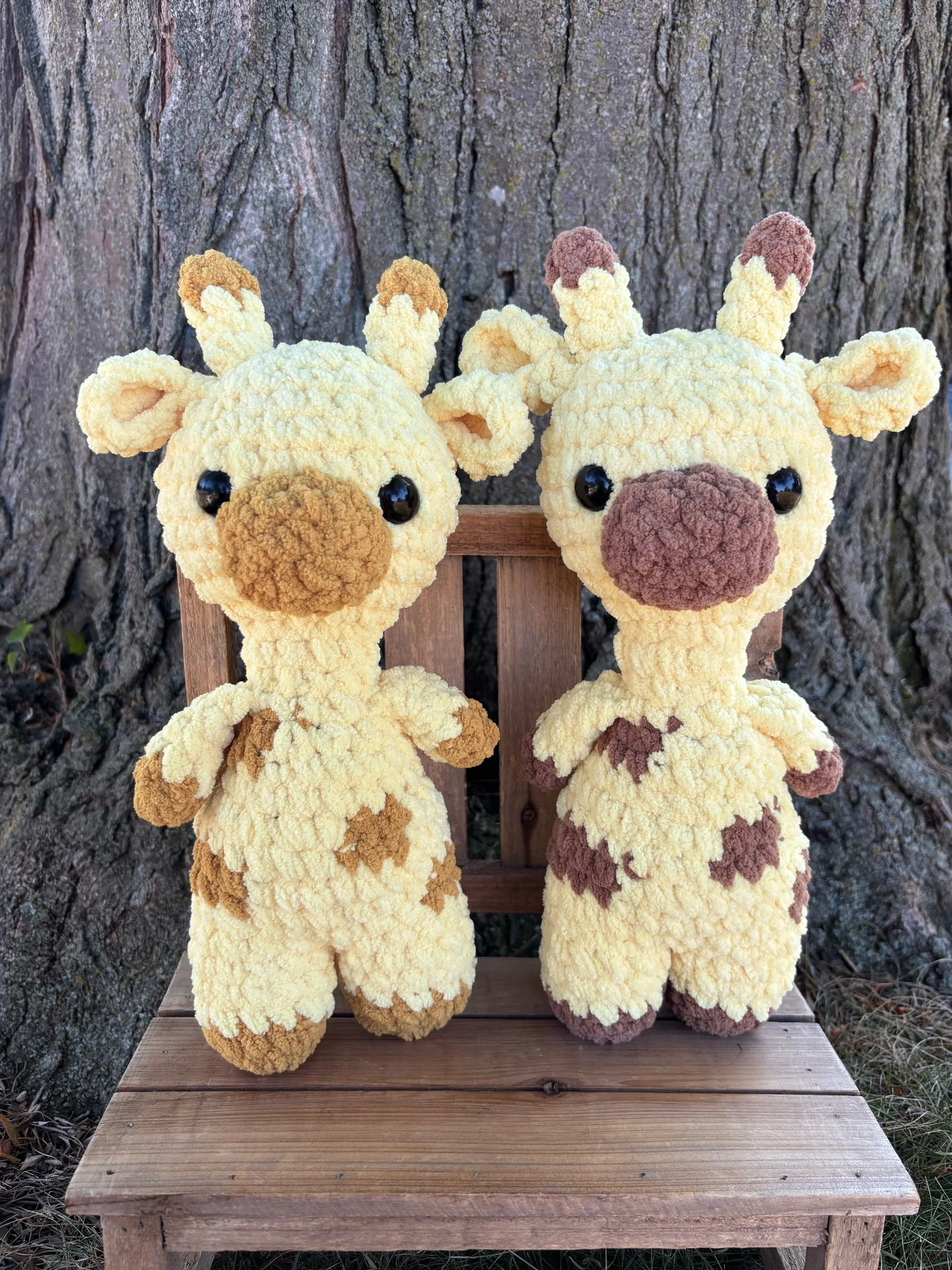 Two crochet giraffe plushies in tan and brown spot colorways side by side