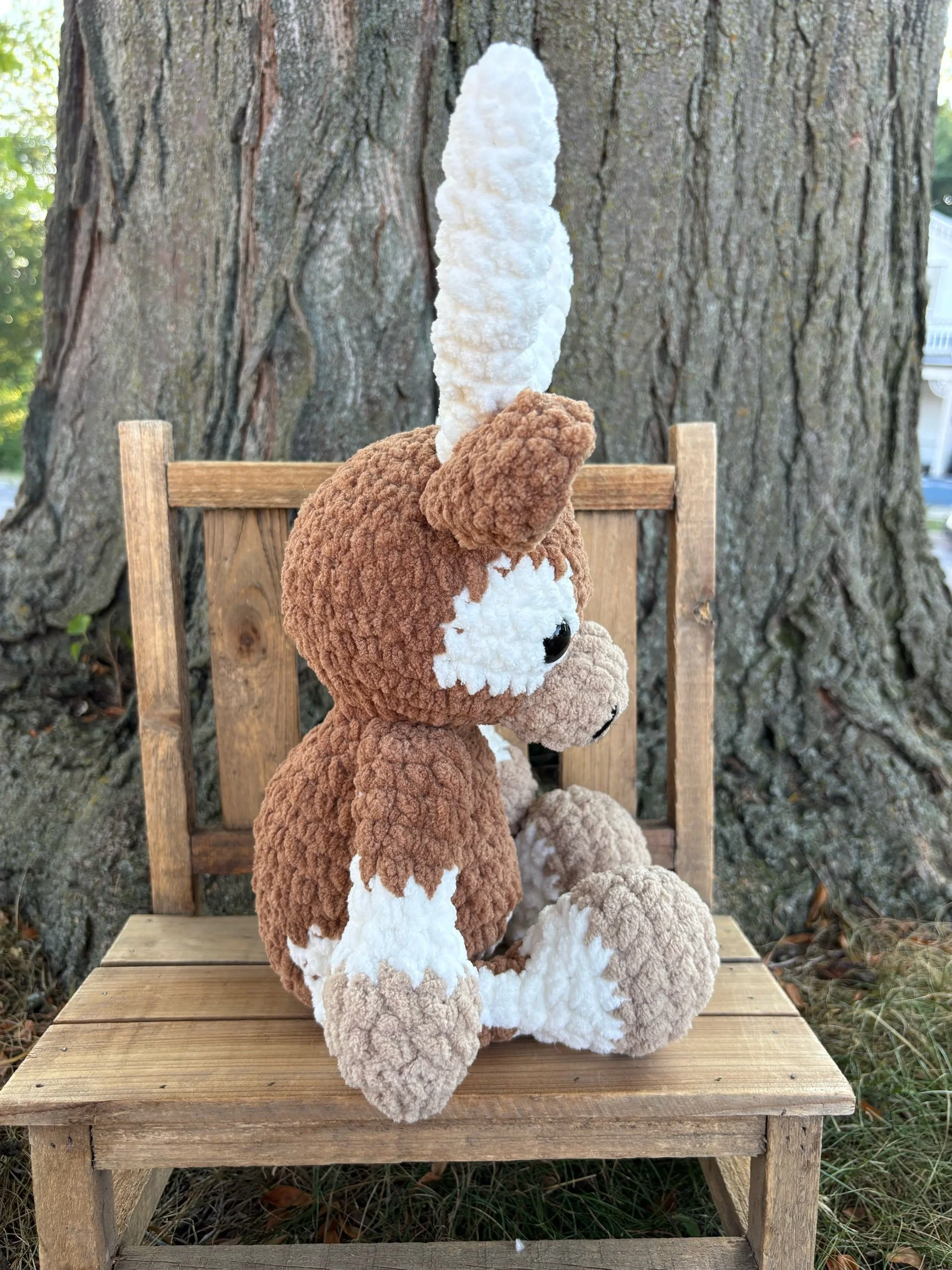 Side view of crochet longhorn plushie showing horns and tail