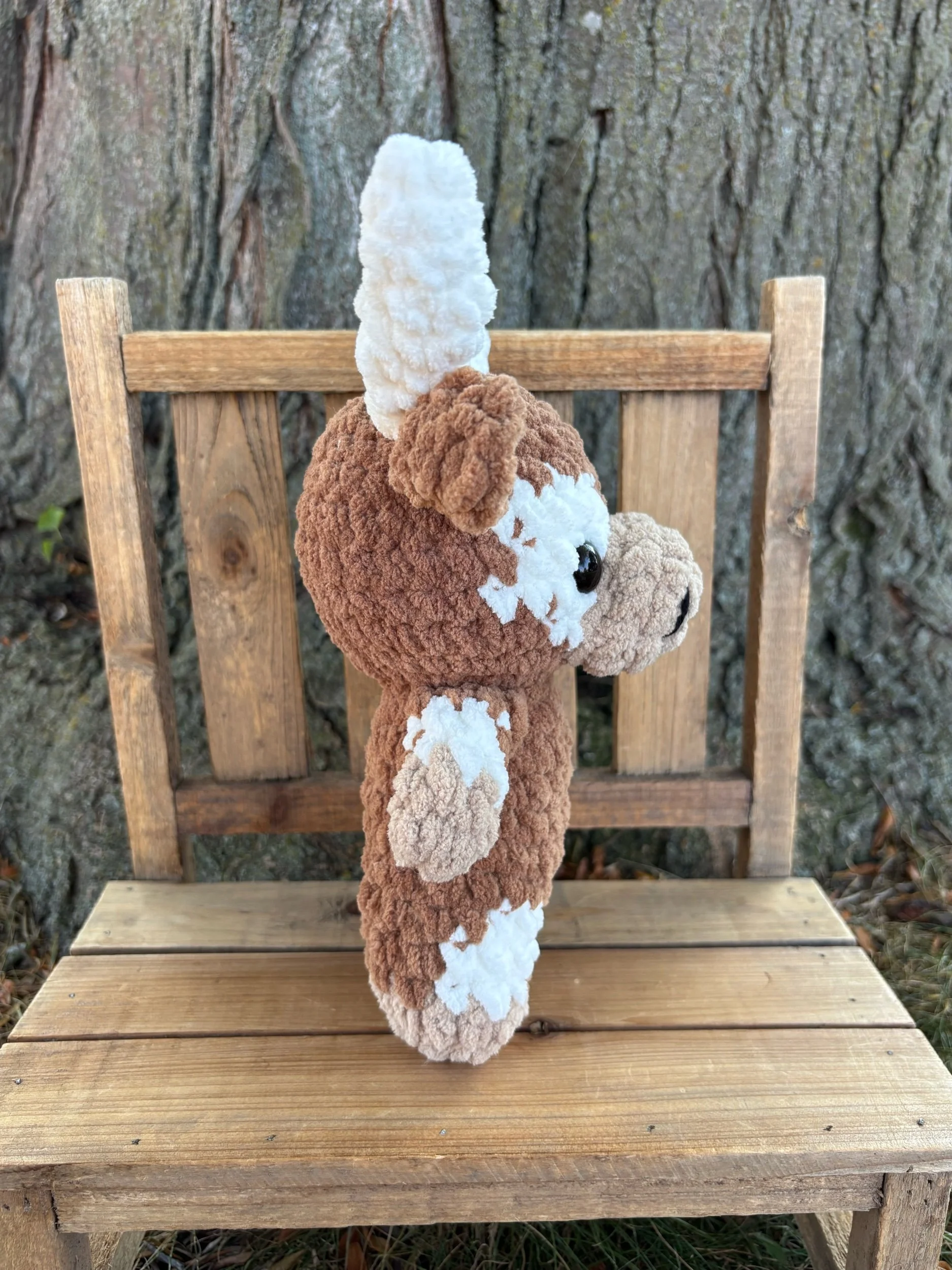 Side view of crochet longhorn plushie showing horns and tail