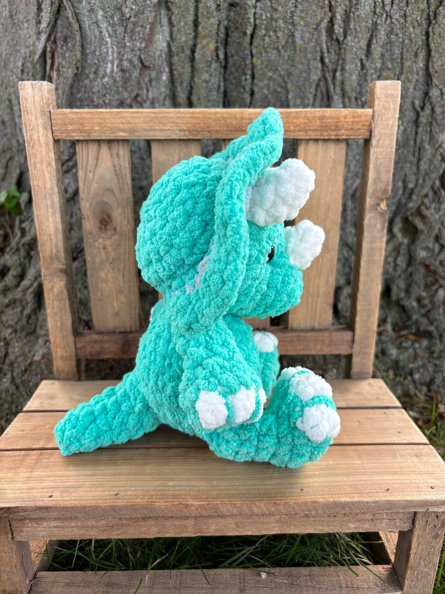 Side view of handmade crochet triceratops plushie showing tail and frill detail