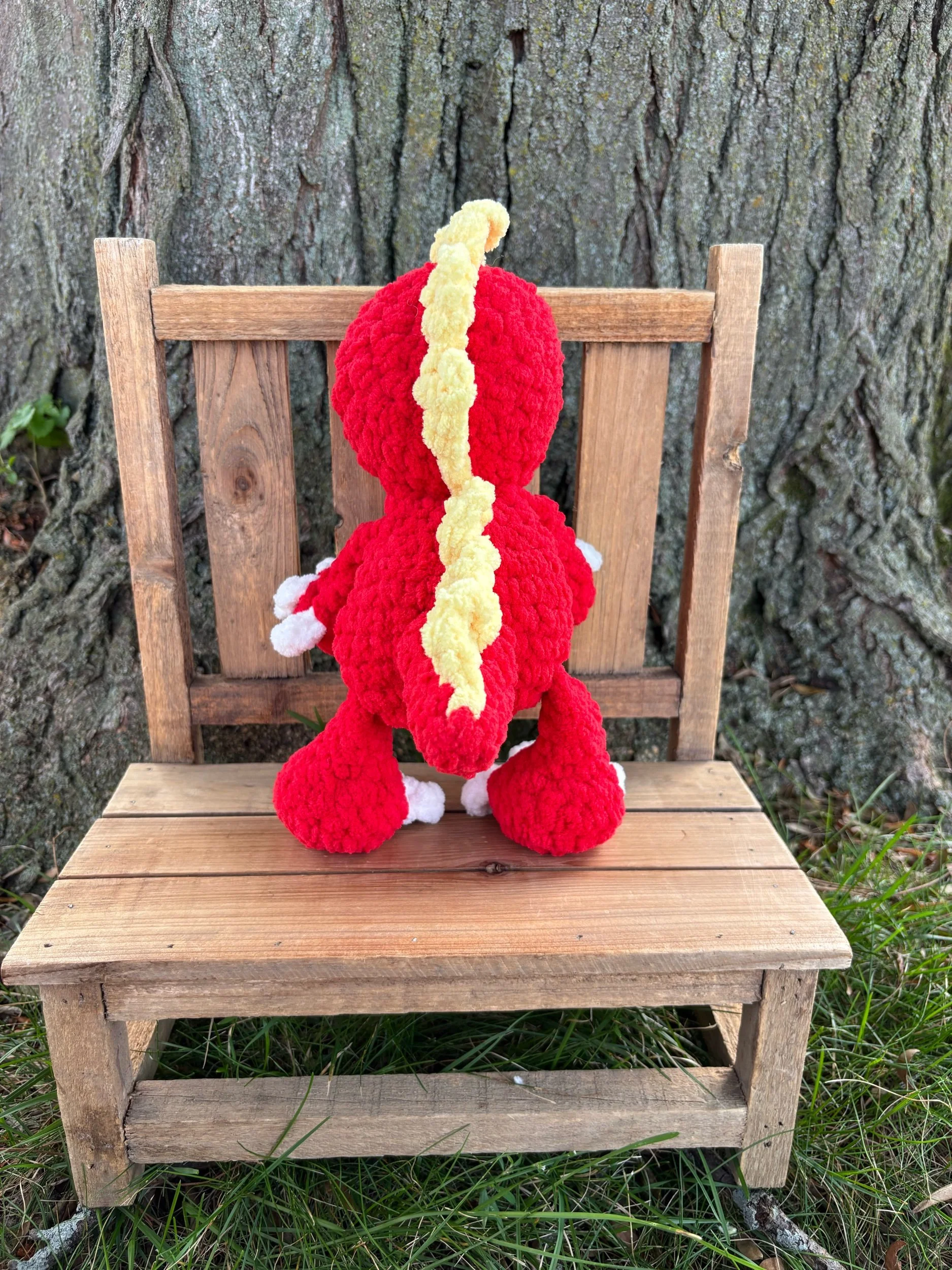 Back view of handmade crochet T-Rex plushie showing yellow spike row down the spine