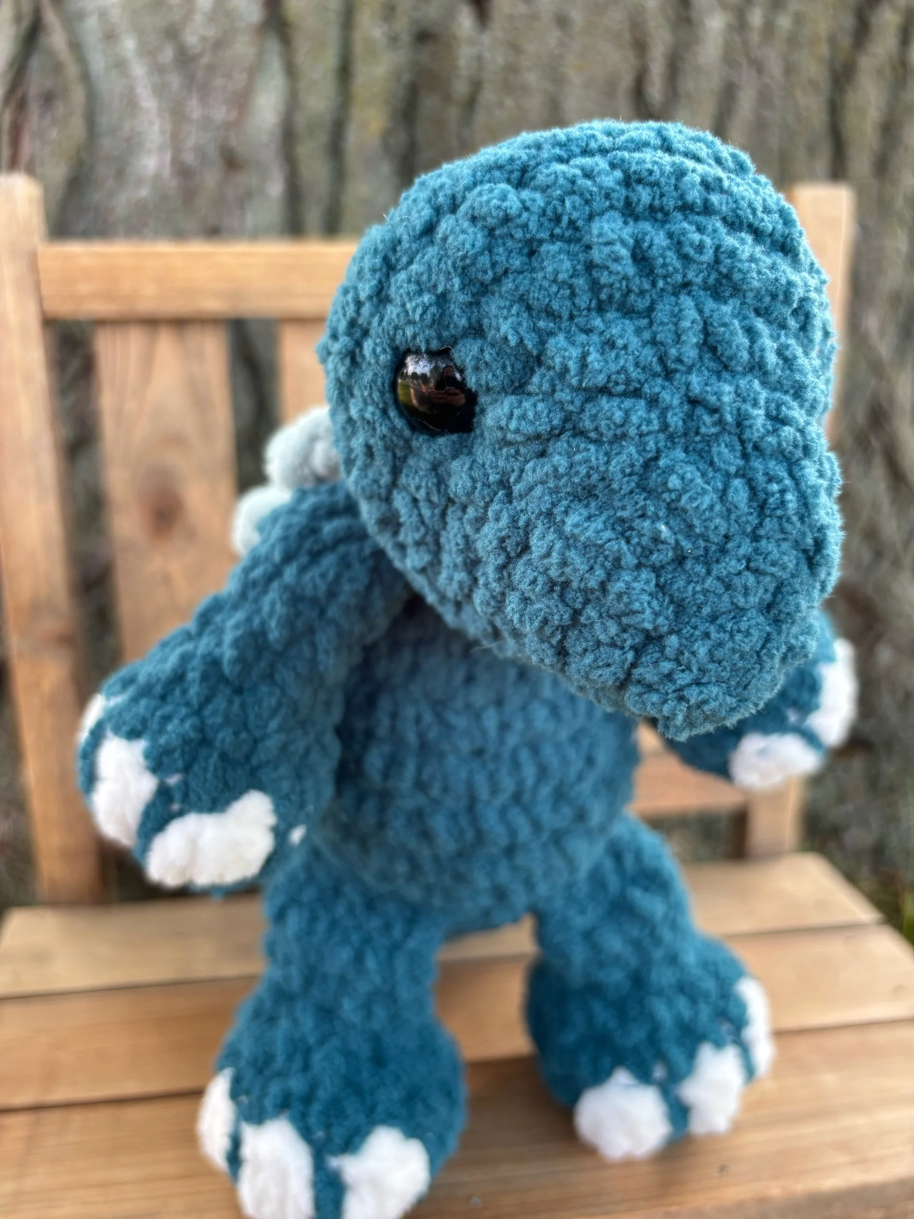 Handmade crochet stegosaurus plushie in teal blue with light blue back plates