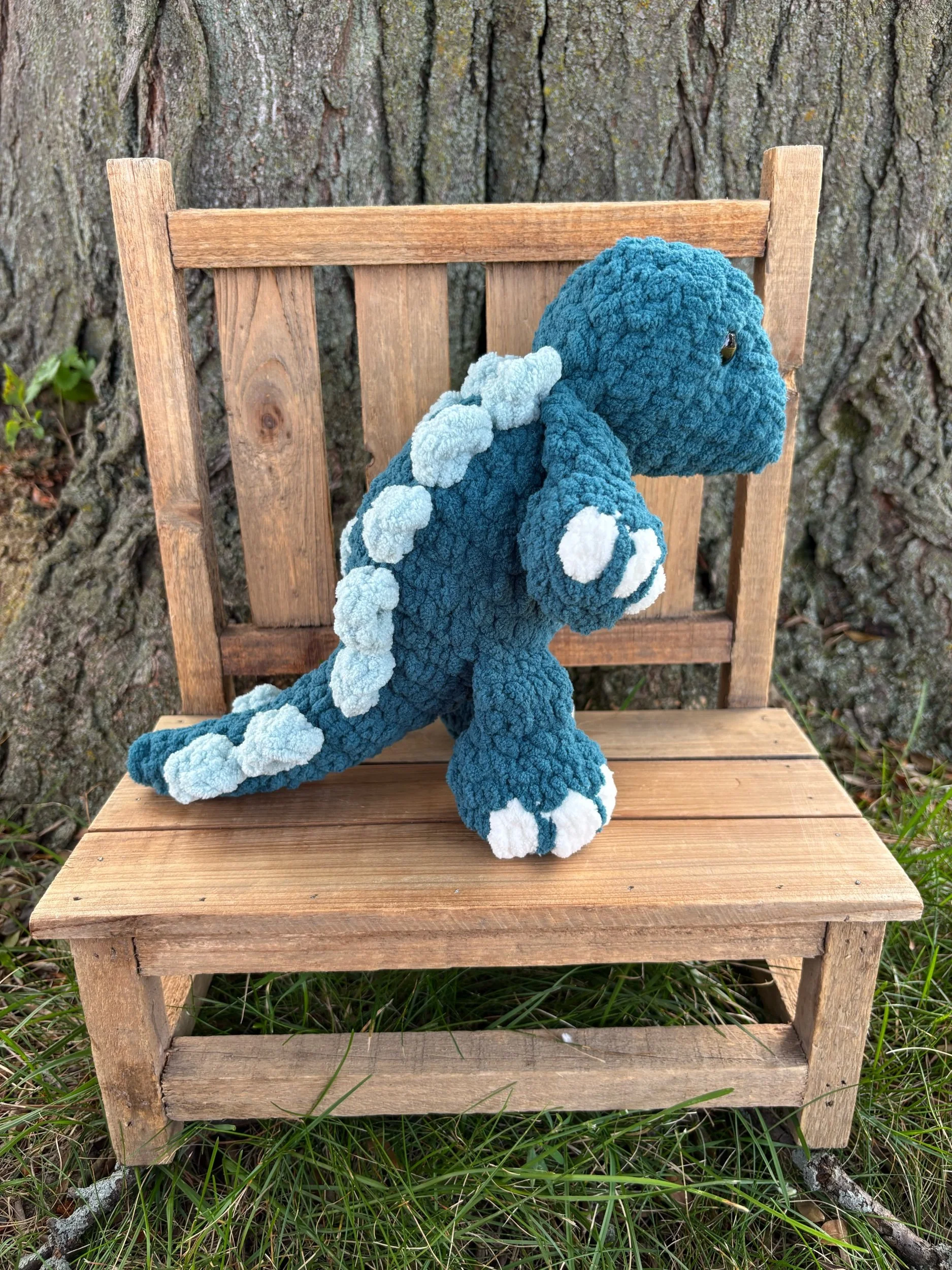 Side view of handmade crochet stegosaurus plushie showing plate row along spine and tail