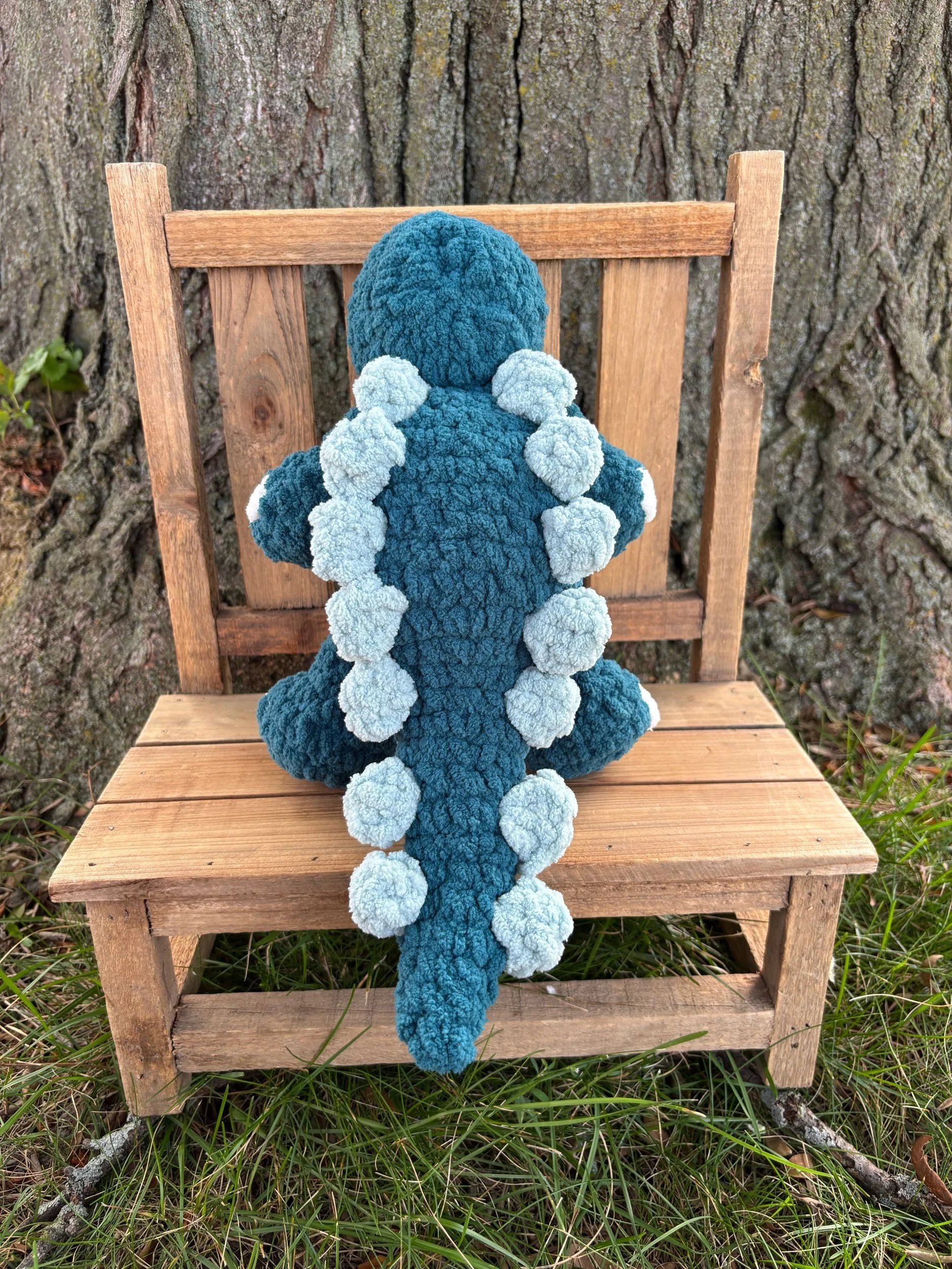 Side view of handmade crochet stegosaurus plushie showing plate row along spine and tail