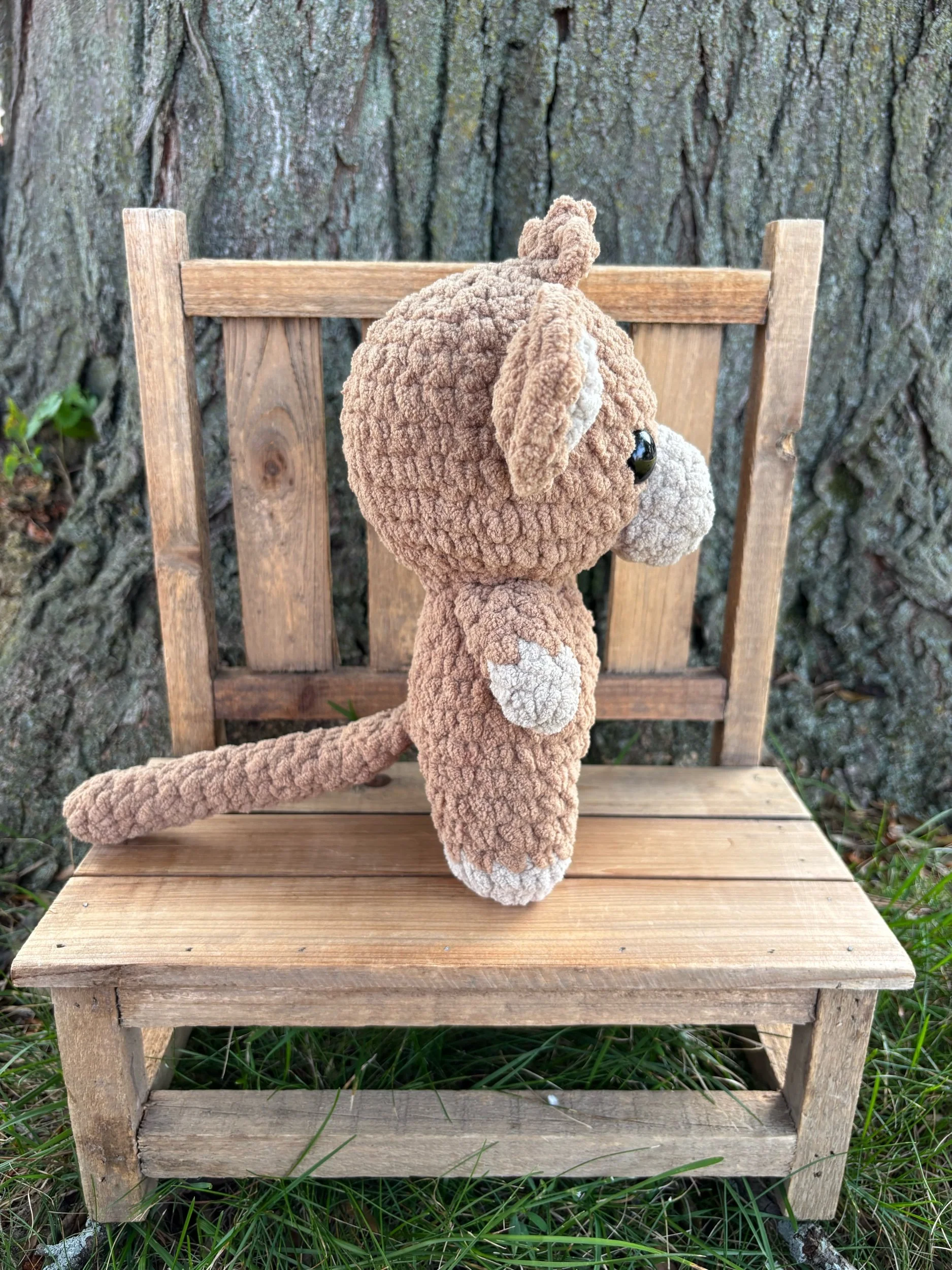 Side view of handmade crochet monkey plushie showing tail and ear detail