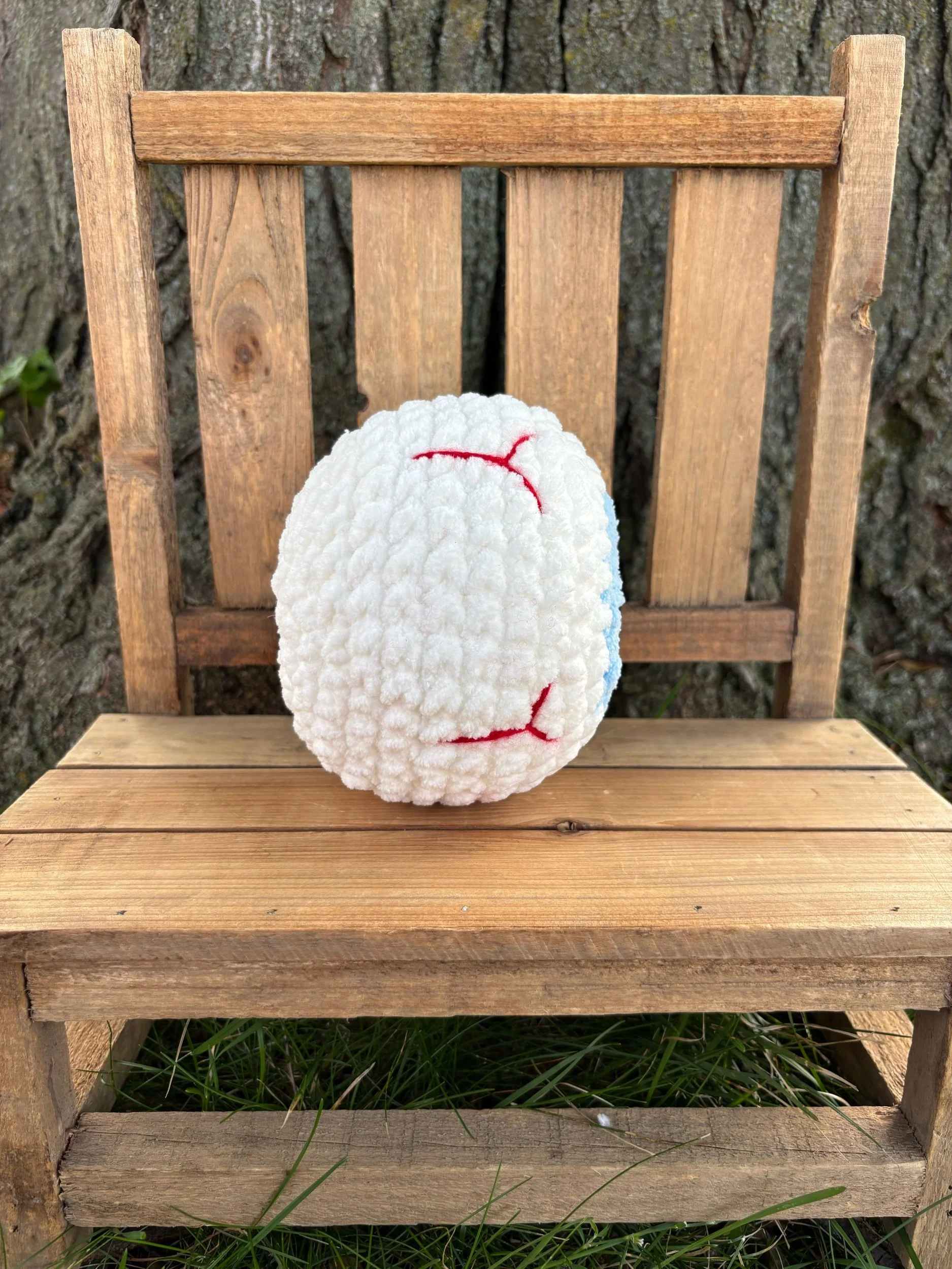 Side view of handmade crochet eyeball plushie showing red vein detail