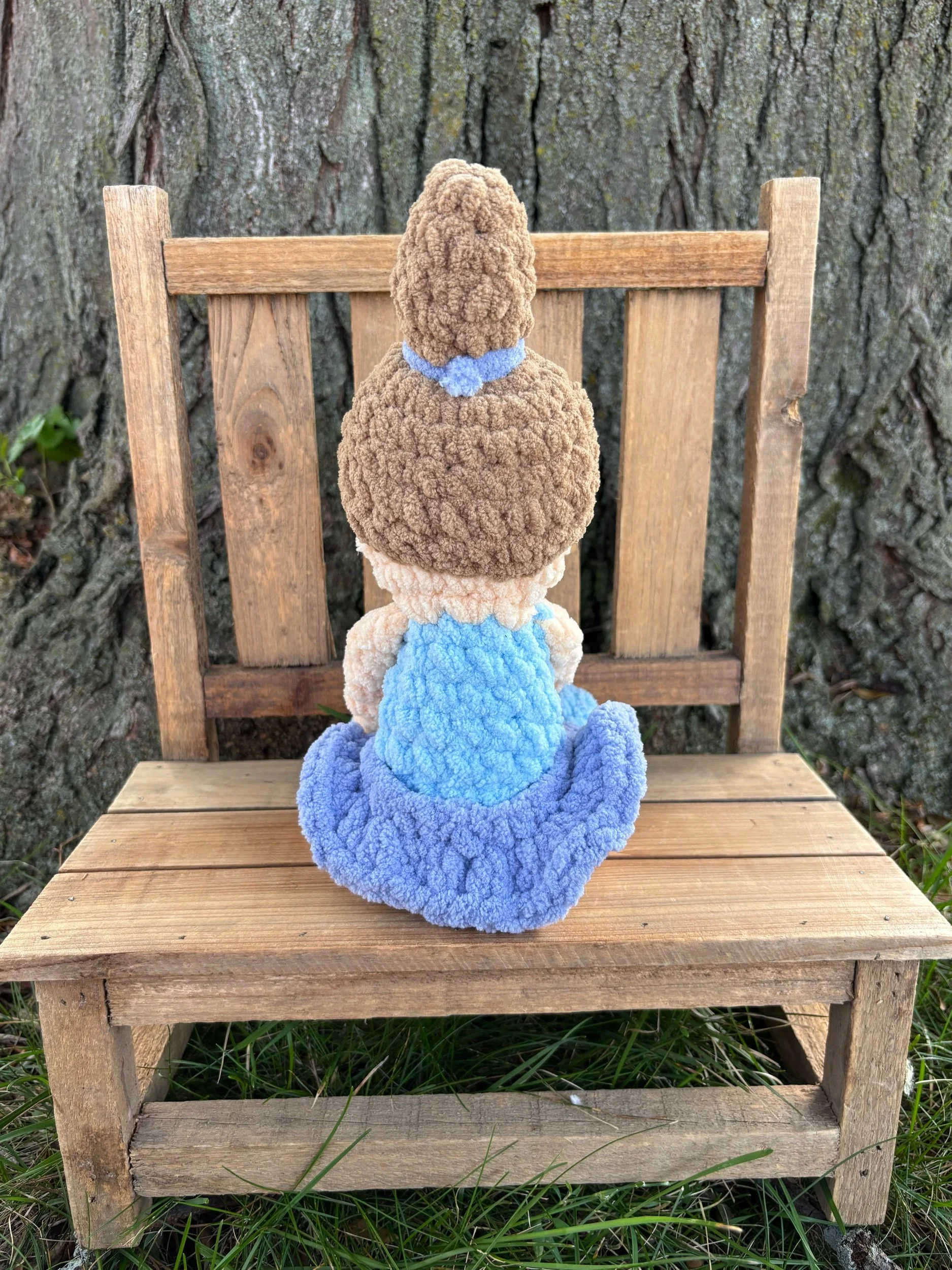 Back view of handmade crochet ballerina doll plushie showing brunette ponytail and blue tutu
