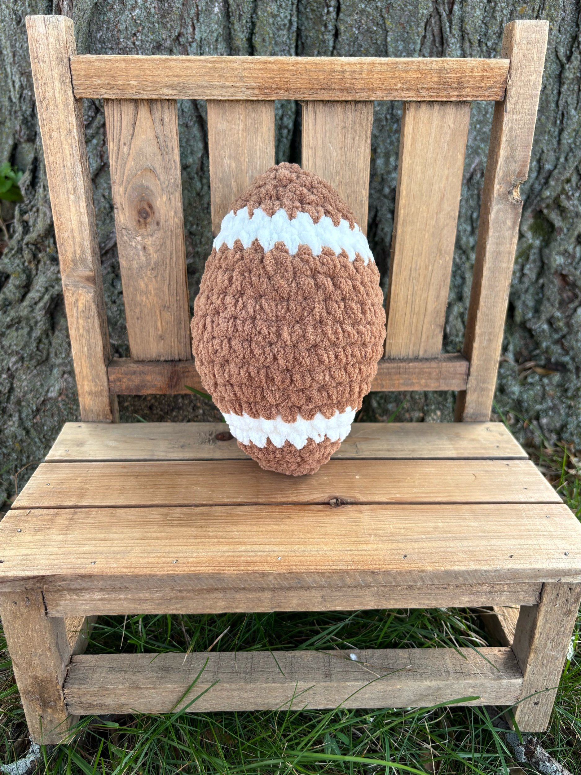 End view of handmade crochet football plushie showing stitched detail and shape