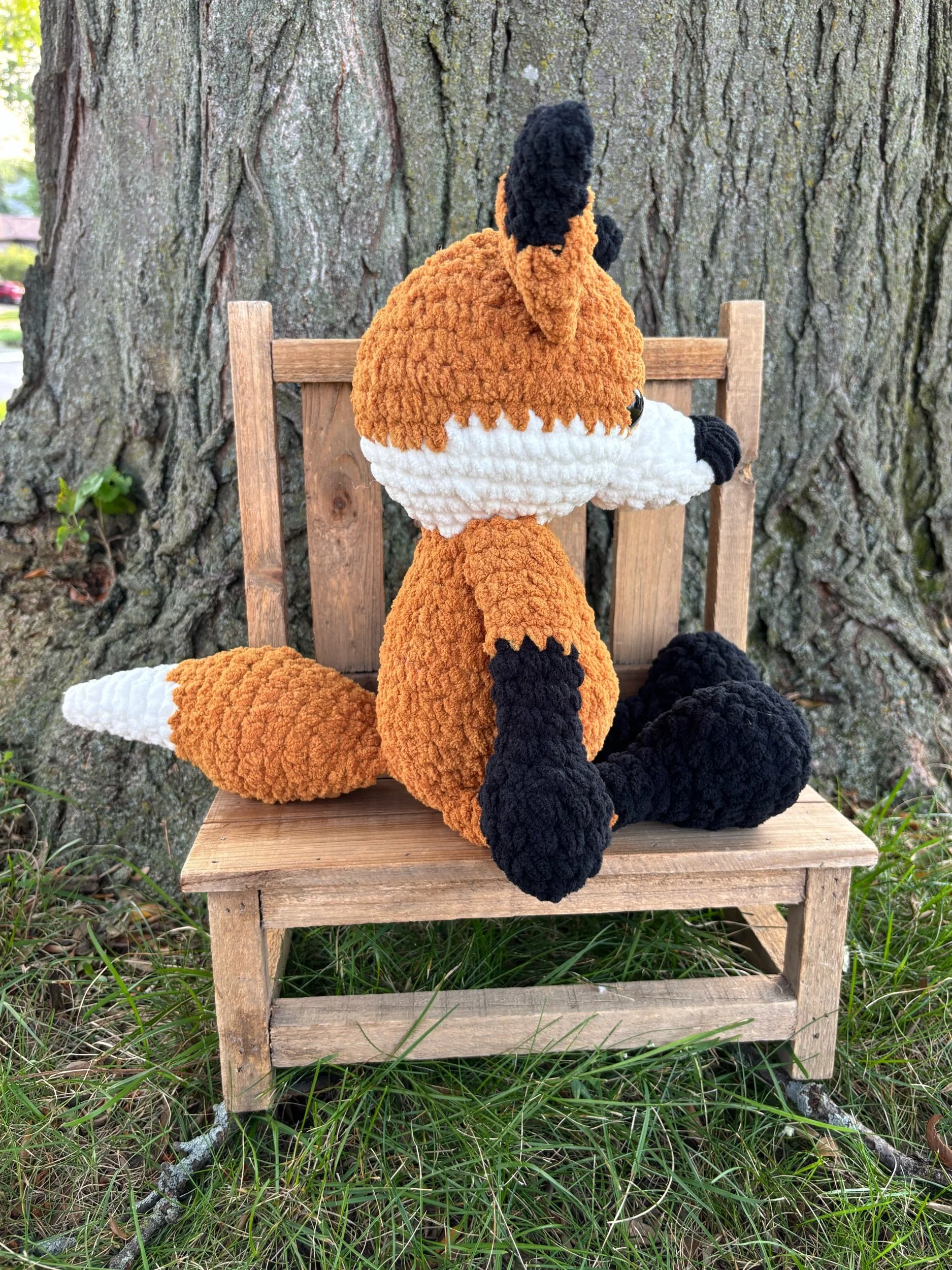 Side view of handmade crochet fox plushie showing white-tipped tail