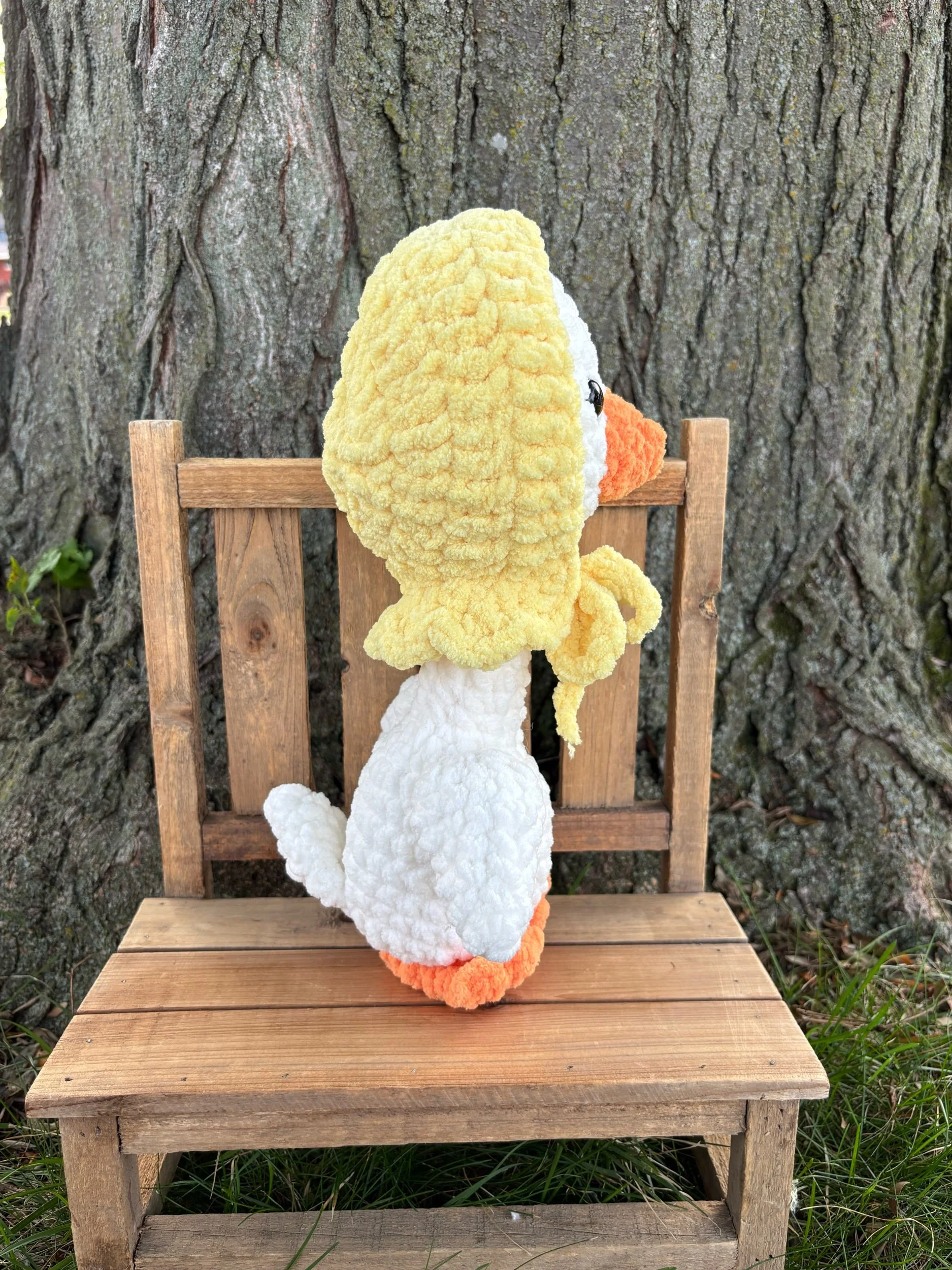 Handmade crochet goose plushie in white with orange bill and yellow tied bonnet