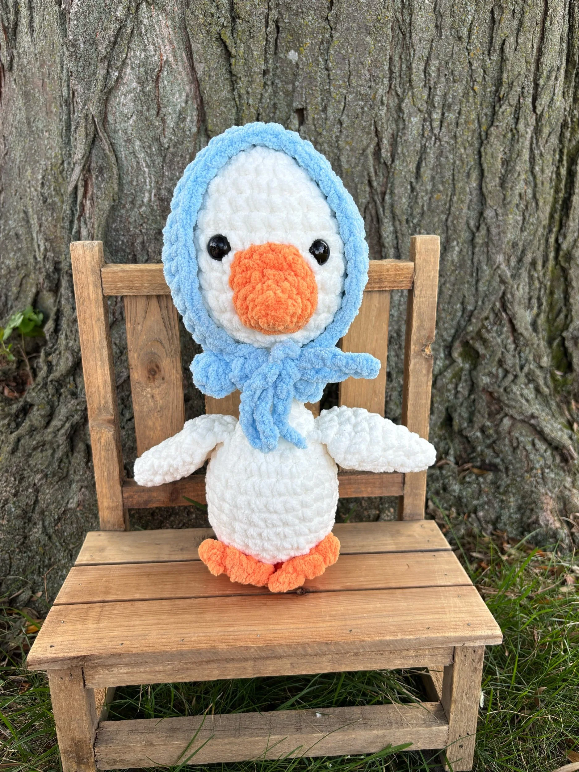 Handmade crochet goose plushie in white with orange bill and blue tied bonnet