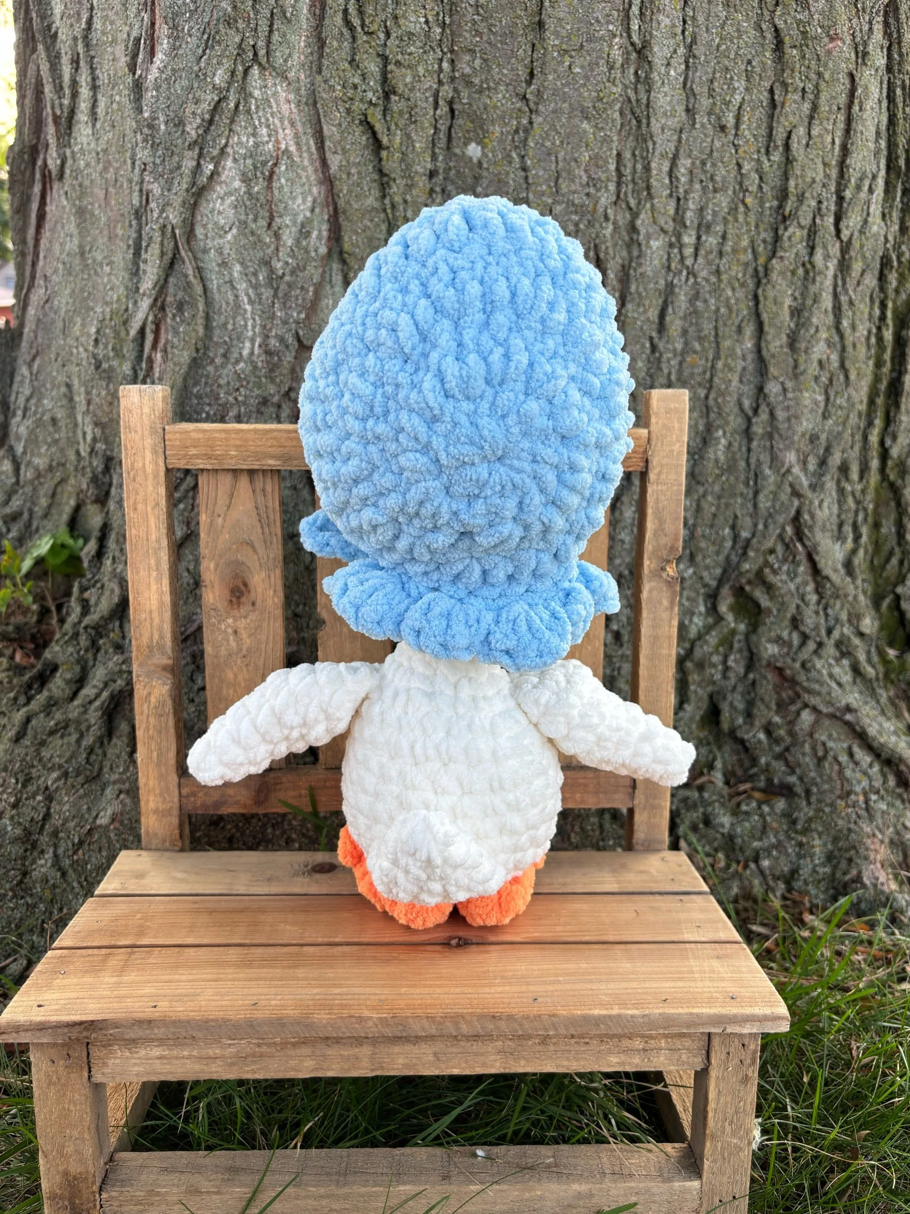 Handmade crochet goose plushie in white with orange bill and blue tied bonnet