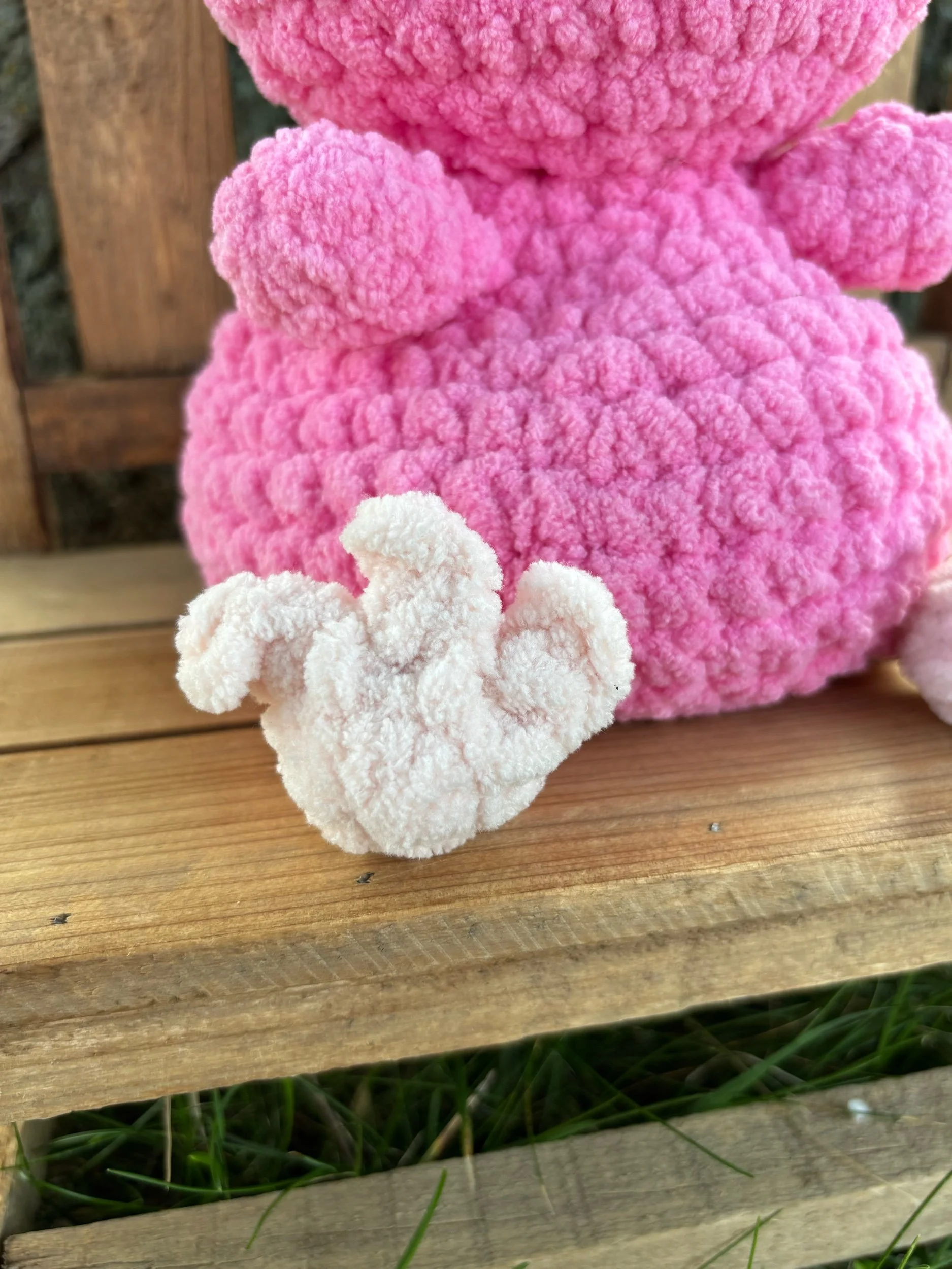 Close-up of pale pink bird feet detail on handmade weighted crochet flamingo plushie