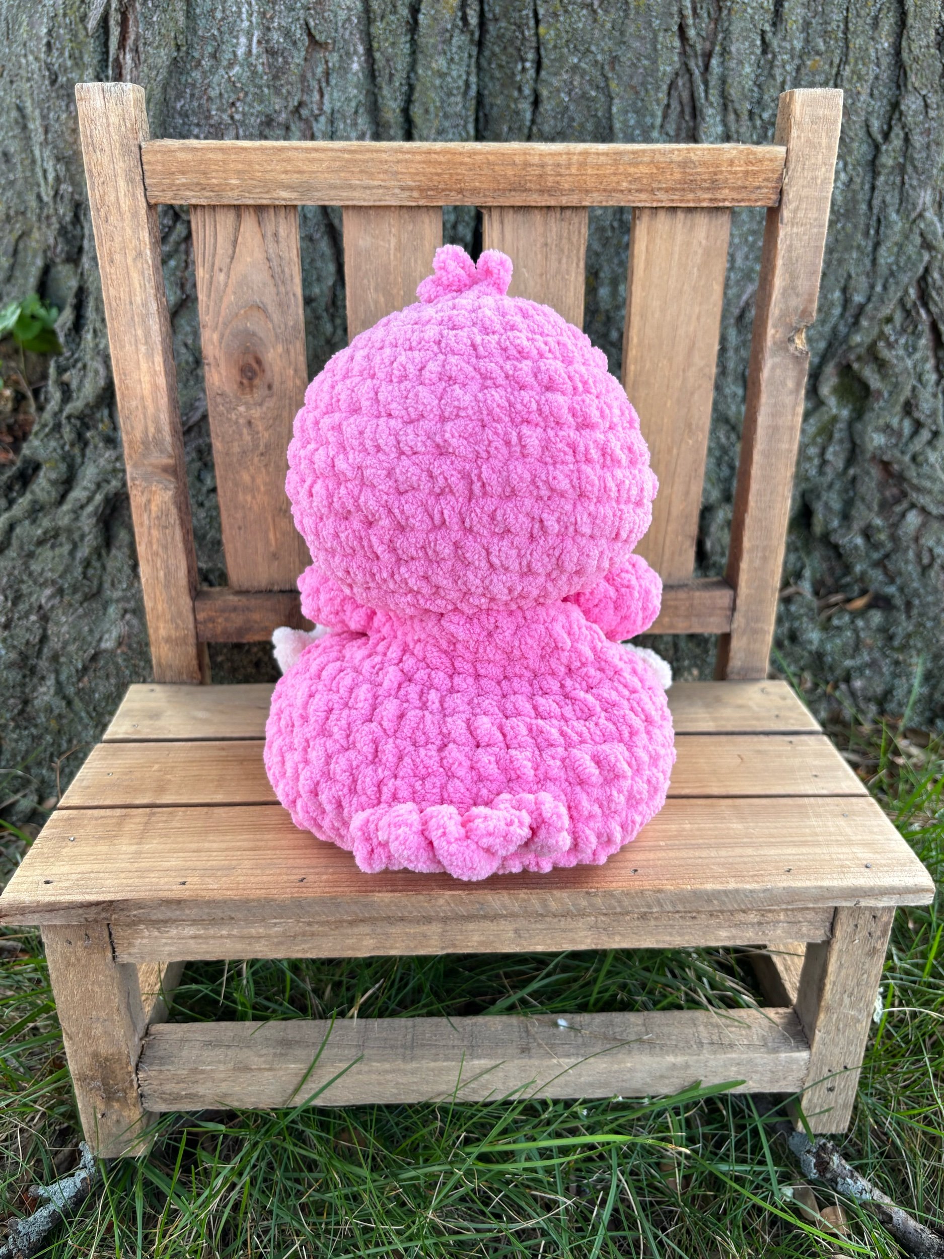 Back view of handmade weighted crochet flamingo plushie showing top knot detail