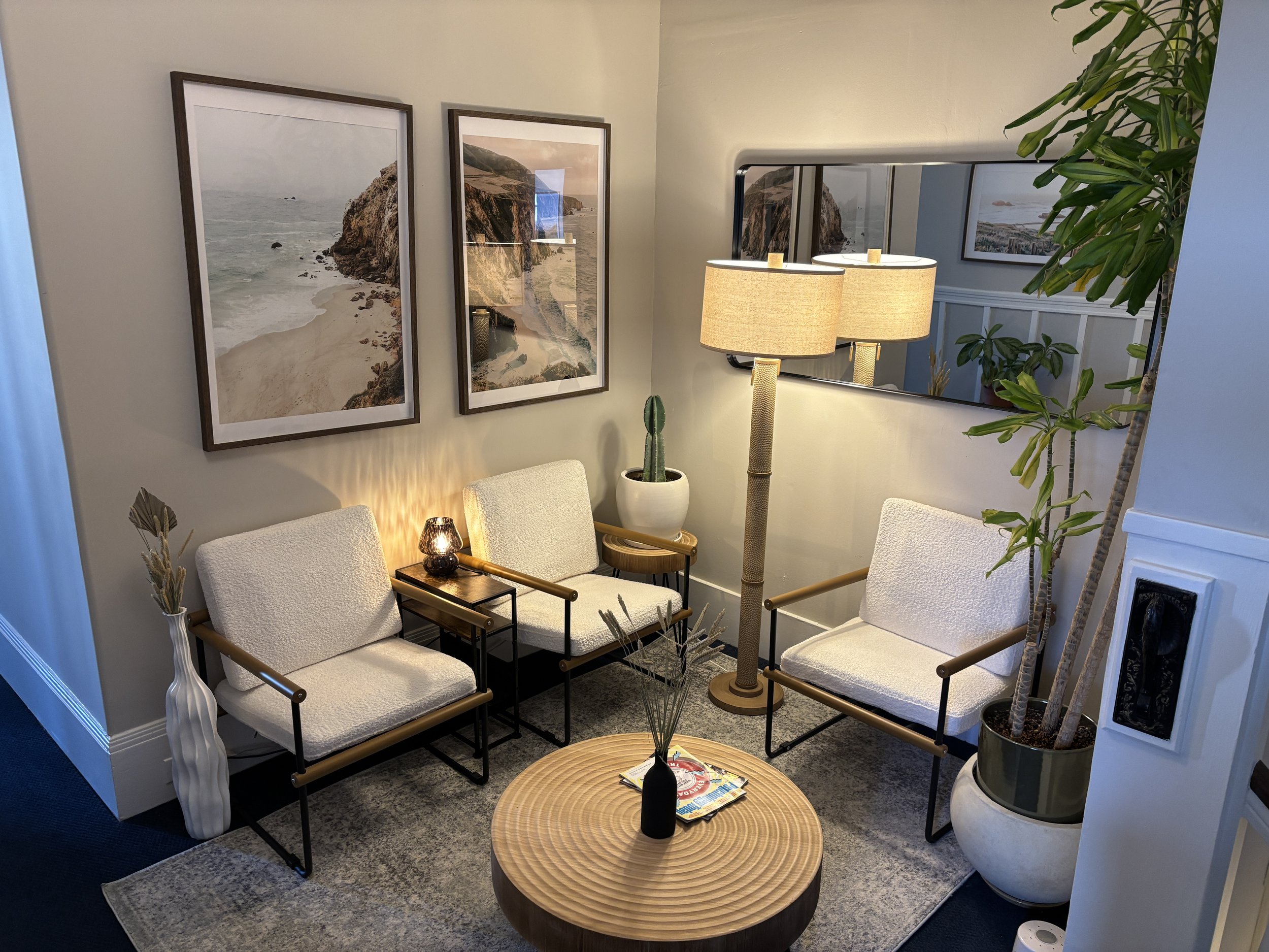 Therapy Office Waiting Area with White chairs, 3 framed photos, and round wood coffee table