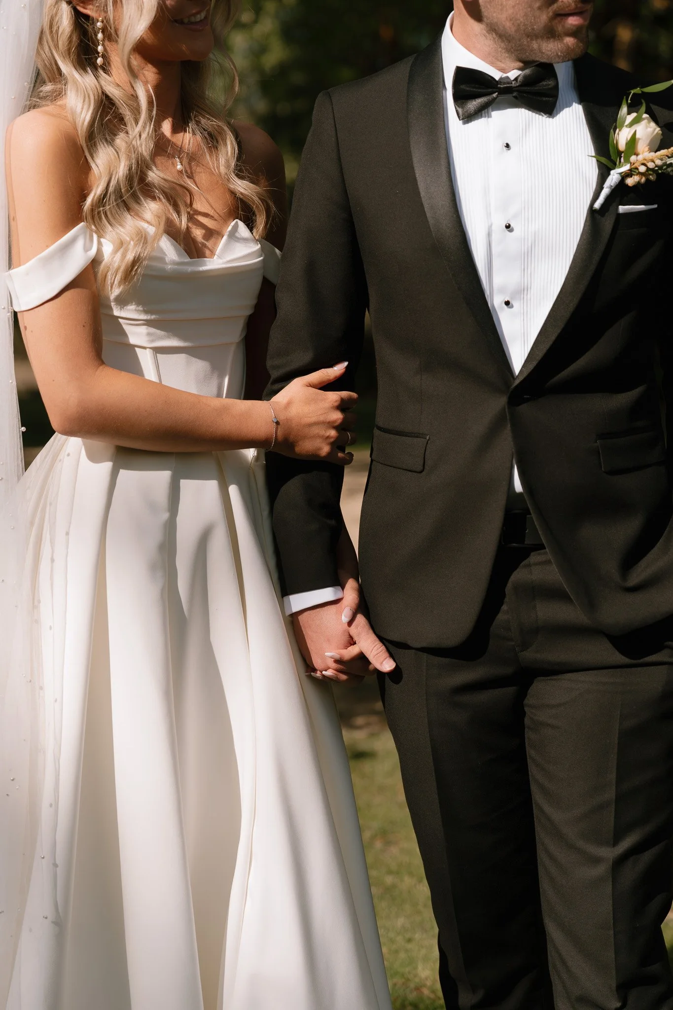 Close-up of bride and groom holding hands during wedding ceremony, focusing on their upper bodies and hands.