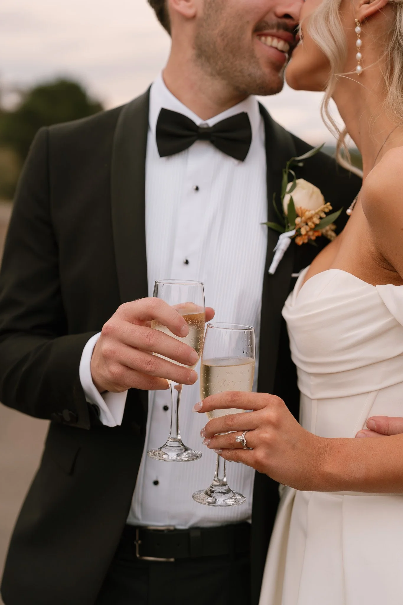 A newlywed couple in wedding attire holding glasses of champagne during their wedding celebration.