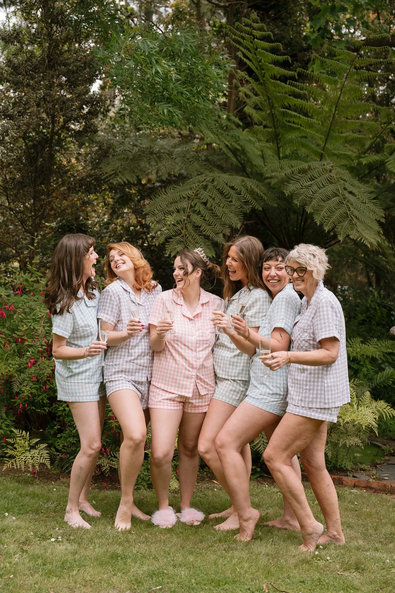 Group of women in pajamas celebrating outdoors with champagne glasses.