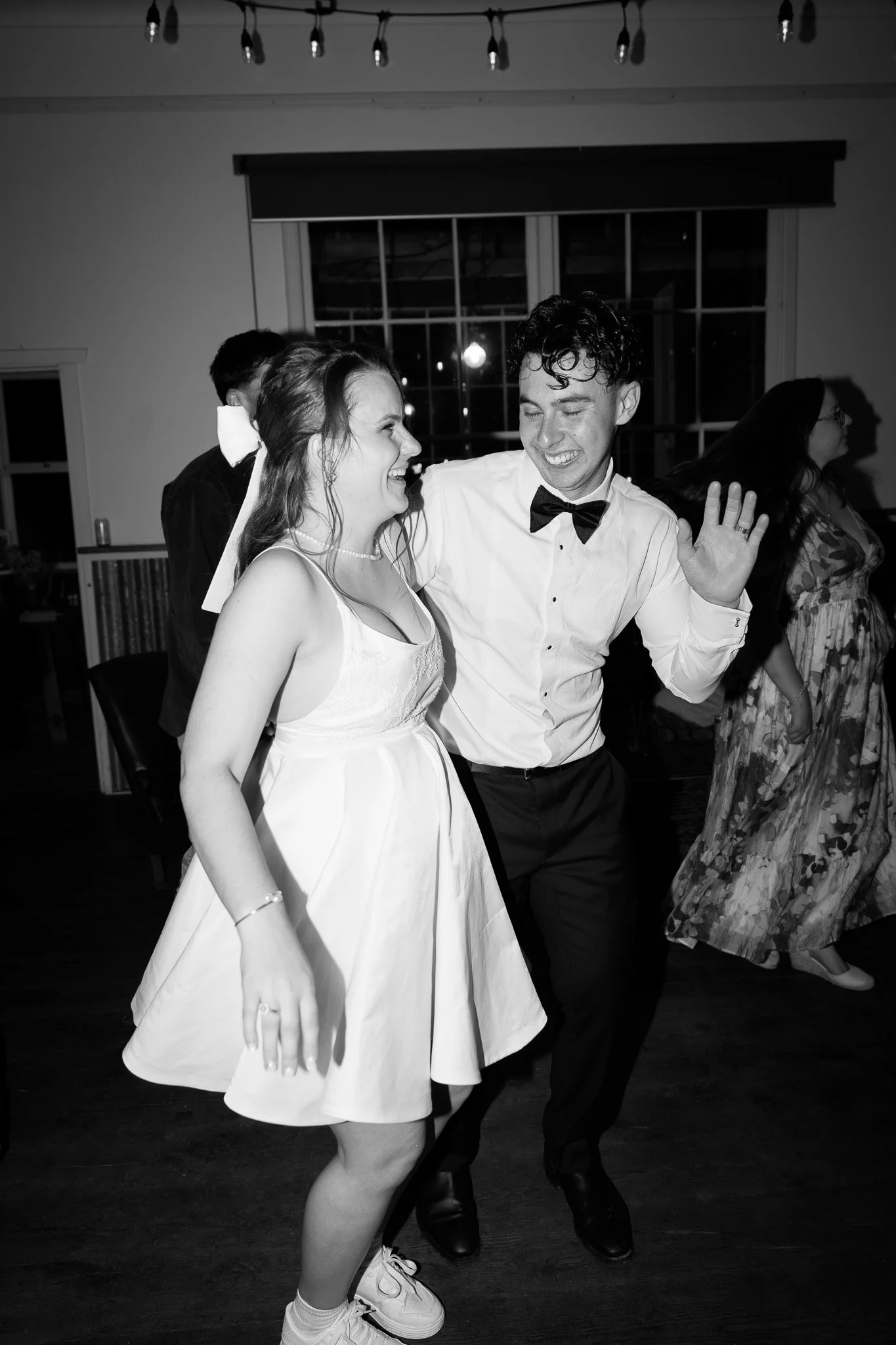 Young couple dancing and smiling at a celebration or party, indoors at night.