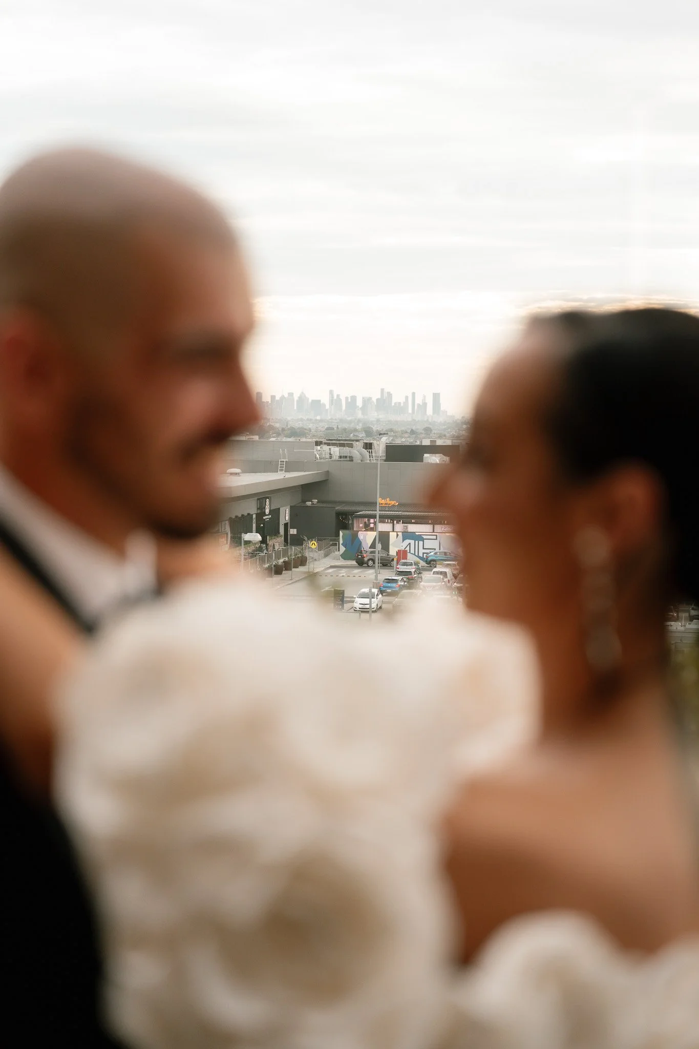 Blurred image of a couple in formal attire with a cityscape in the background.