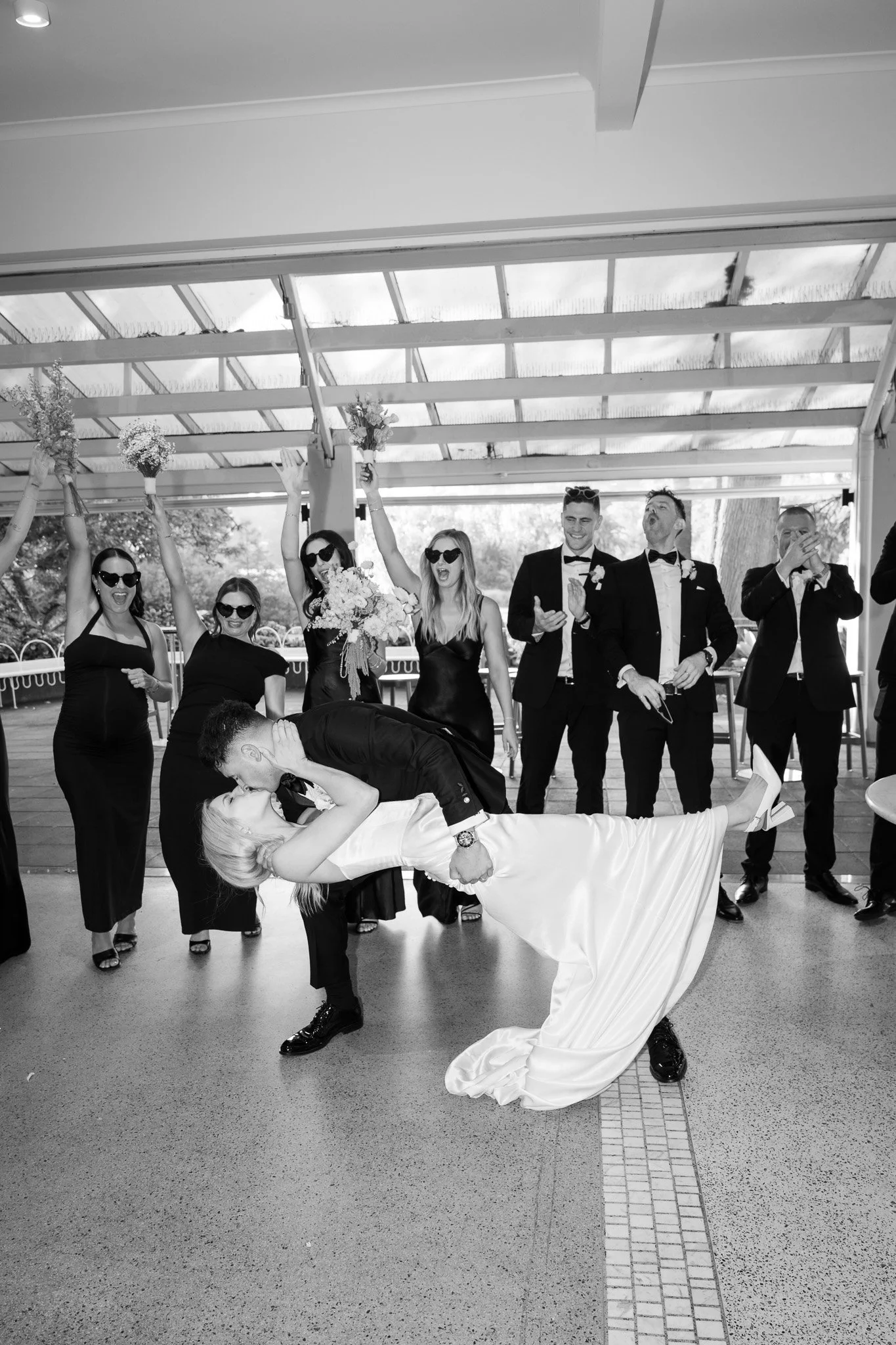 A wedding reception with the bride and groom dancing in front of group of wedding guests, who are clapping and celebrating.