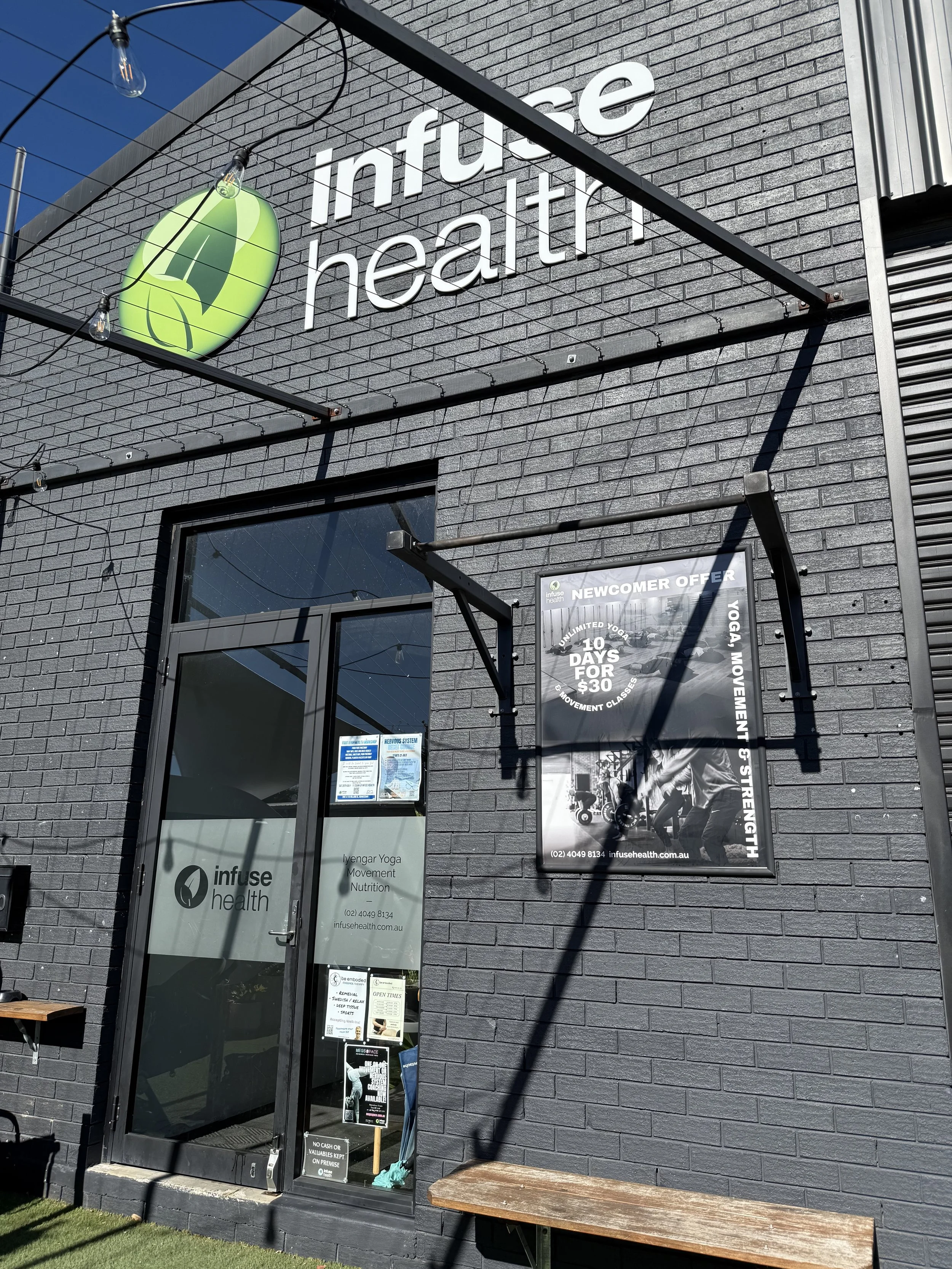 The front of a brick building painted black with a green and white sign reading "infuse health" with dance Newcastle Dance Physiotherapy located inside