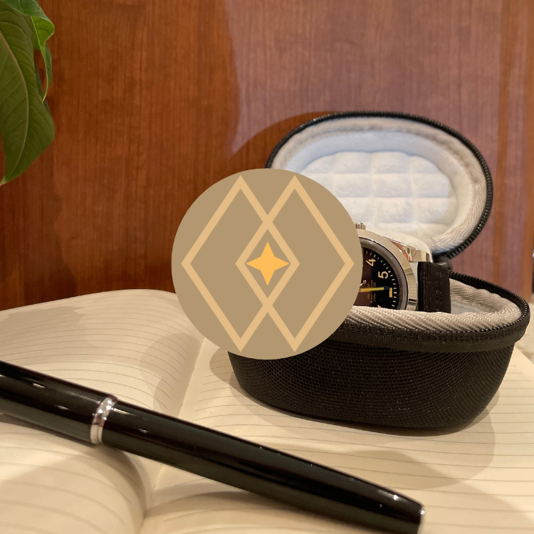 A wristwatch inside a black padded case resting on an open, lined notebook with a black pen nearby, against a wooden surface with a green plant partially visible.